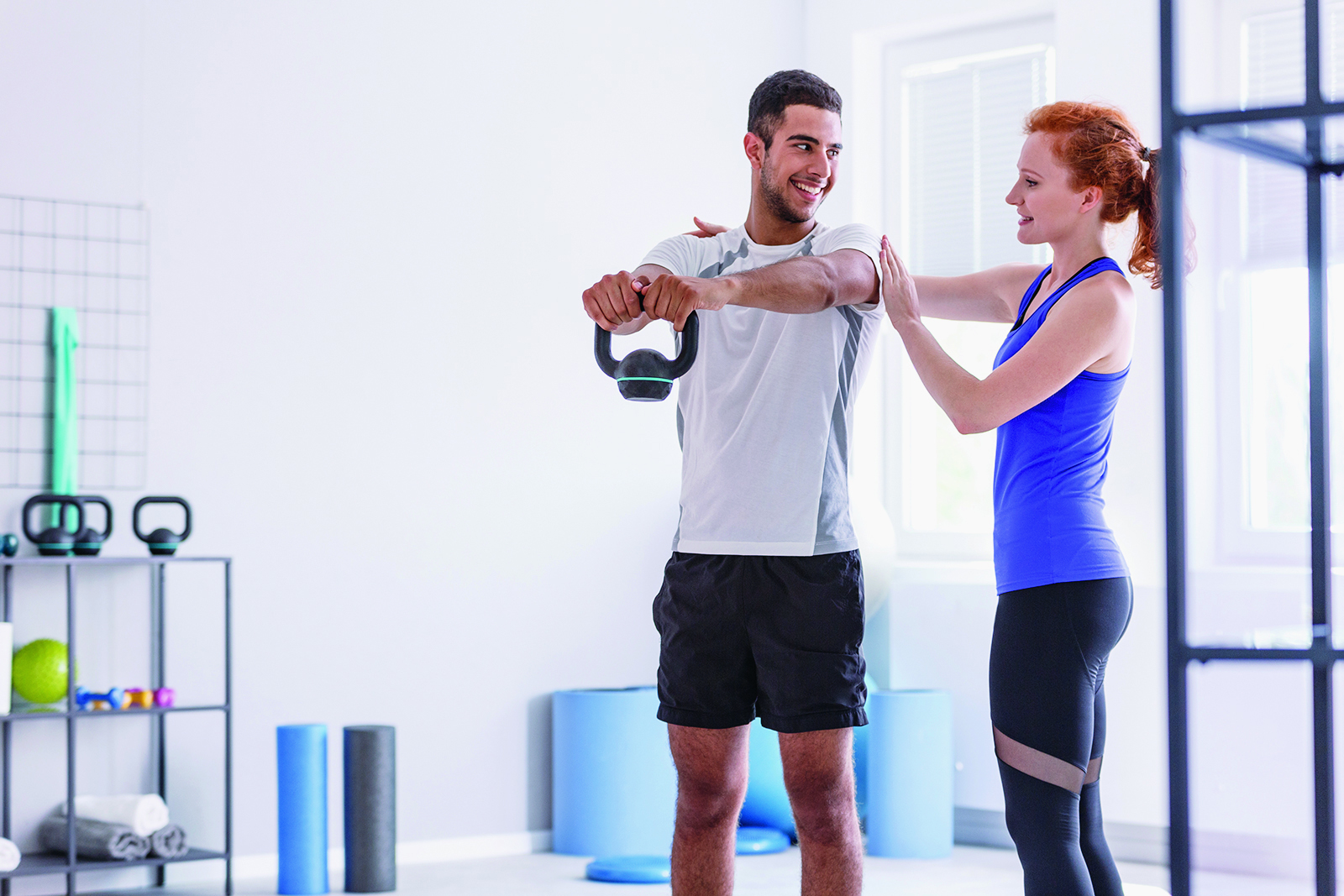 Une kinésiologue aide un athlète avec un mouvement de musculation.