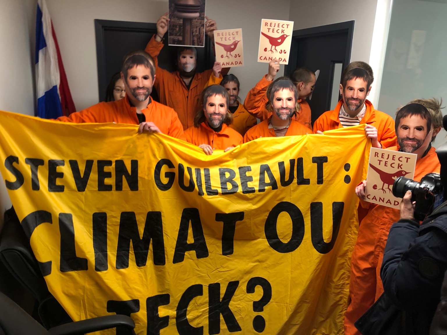 Des militants écologistes habillés en combines oranges occupent les bureaux du ministre du Patrimoine Steven Guilbeault. Ils portent des masques à l'effigie du ministre.