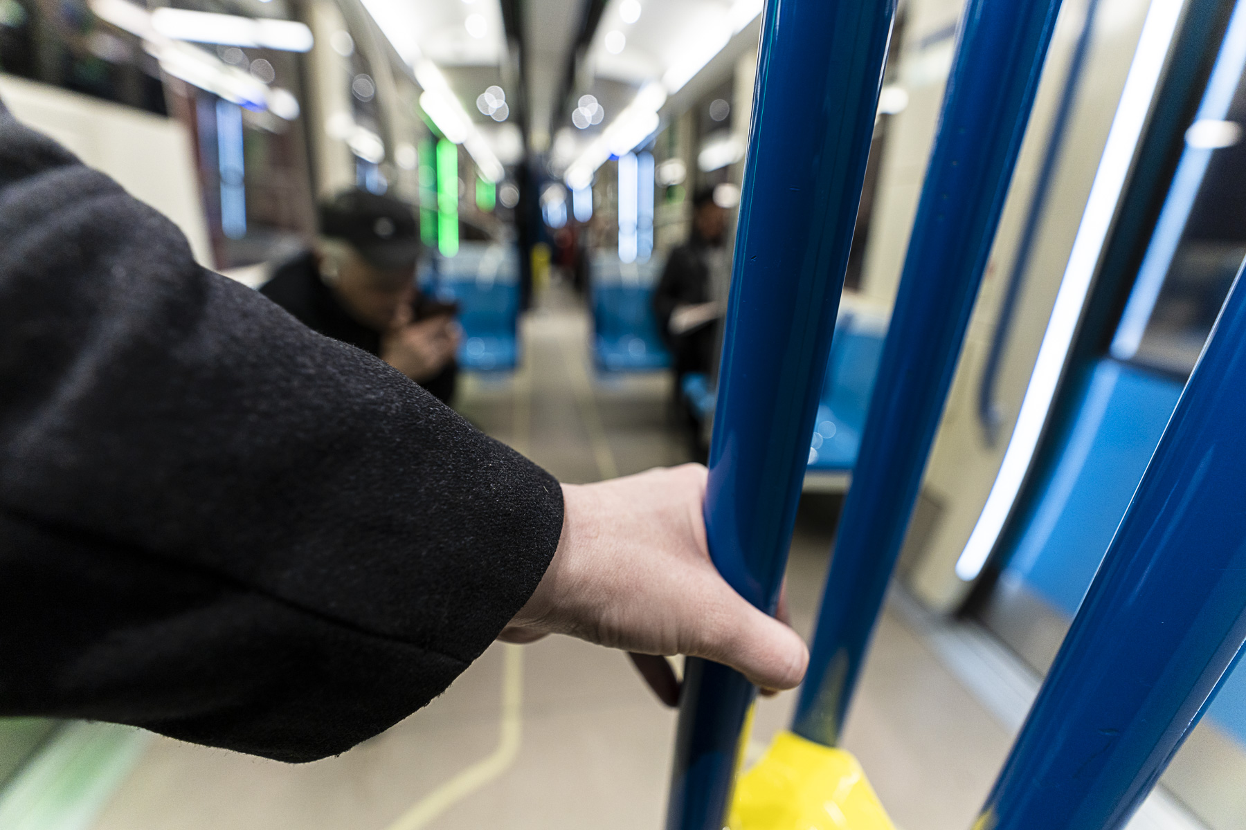 Une personne tient une barre dans un wagon de métro.