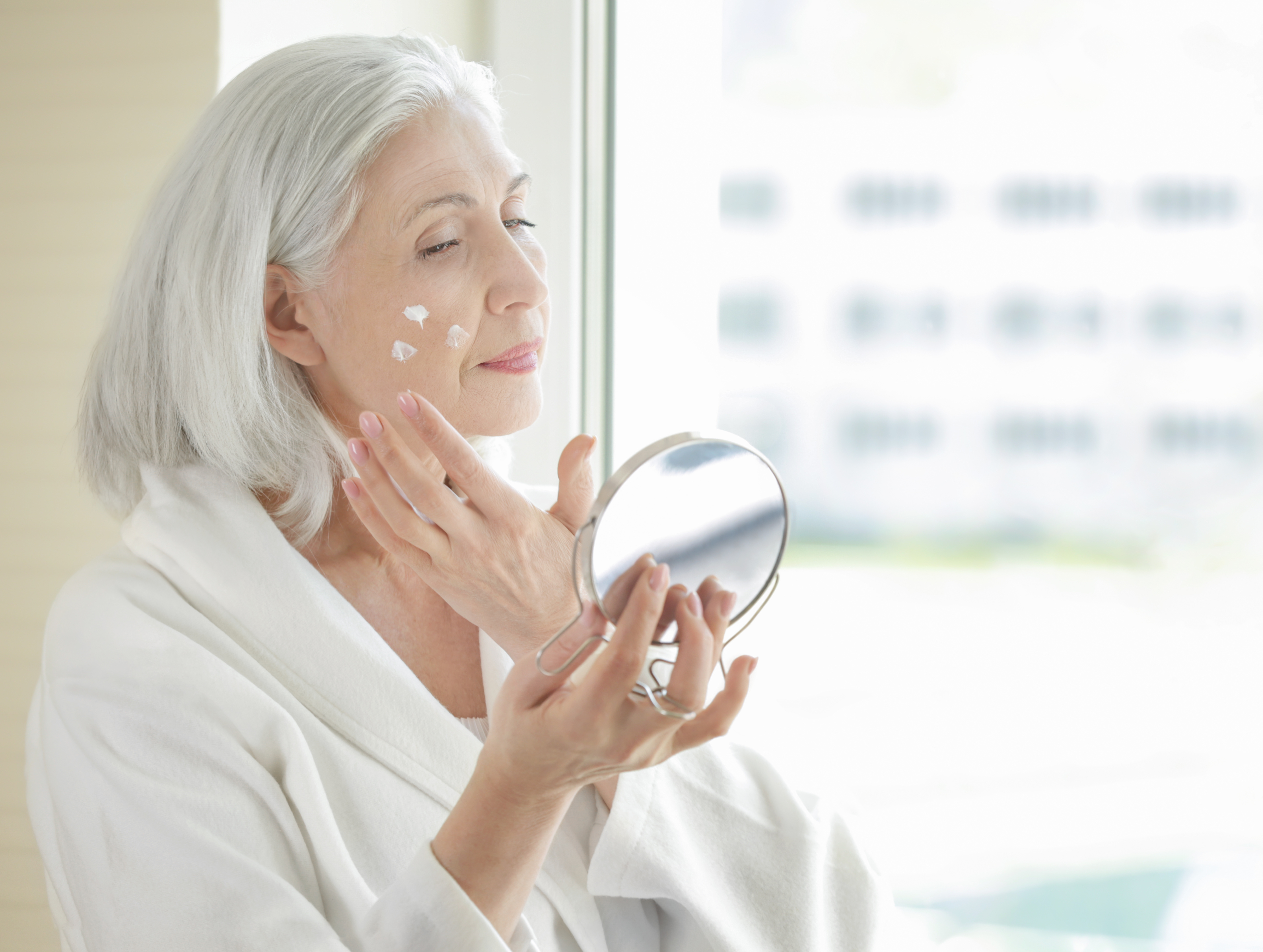 Femme mûre qui applique de la crème sur son visage