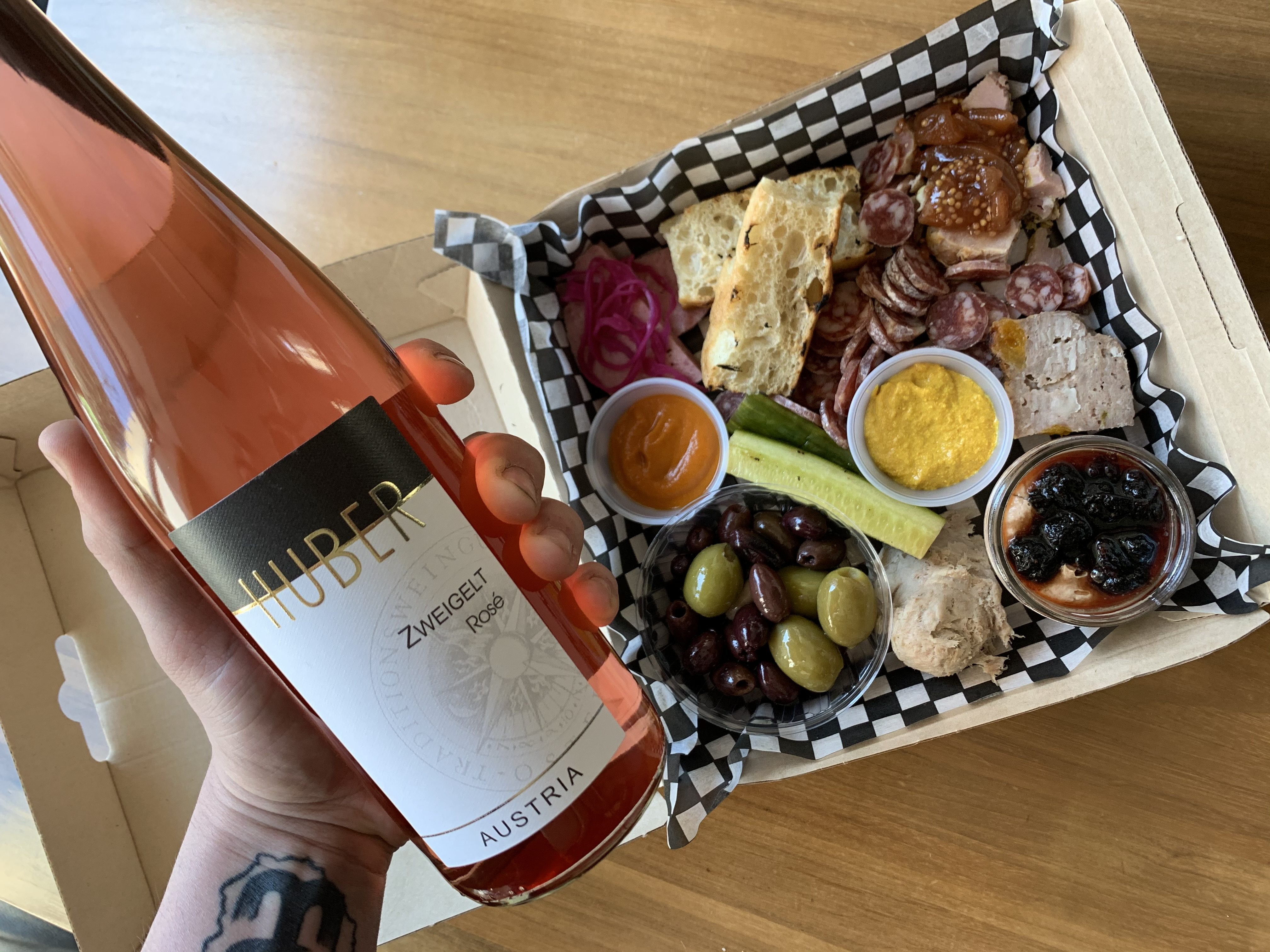 Main qui tient une bouteille de vin et une boîte d'apétitifs