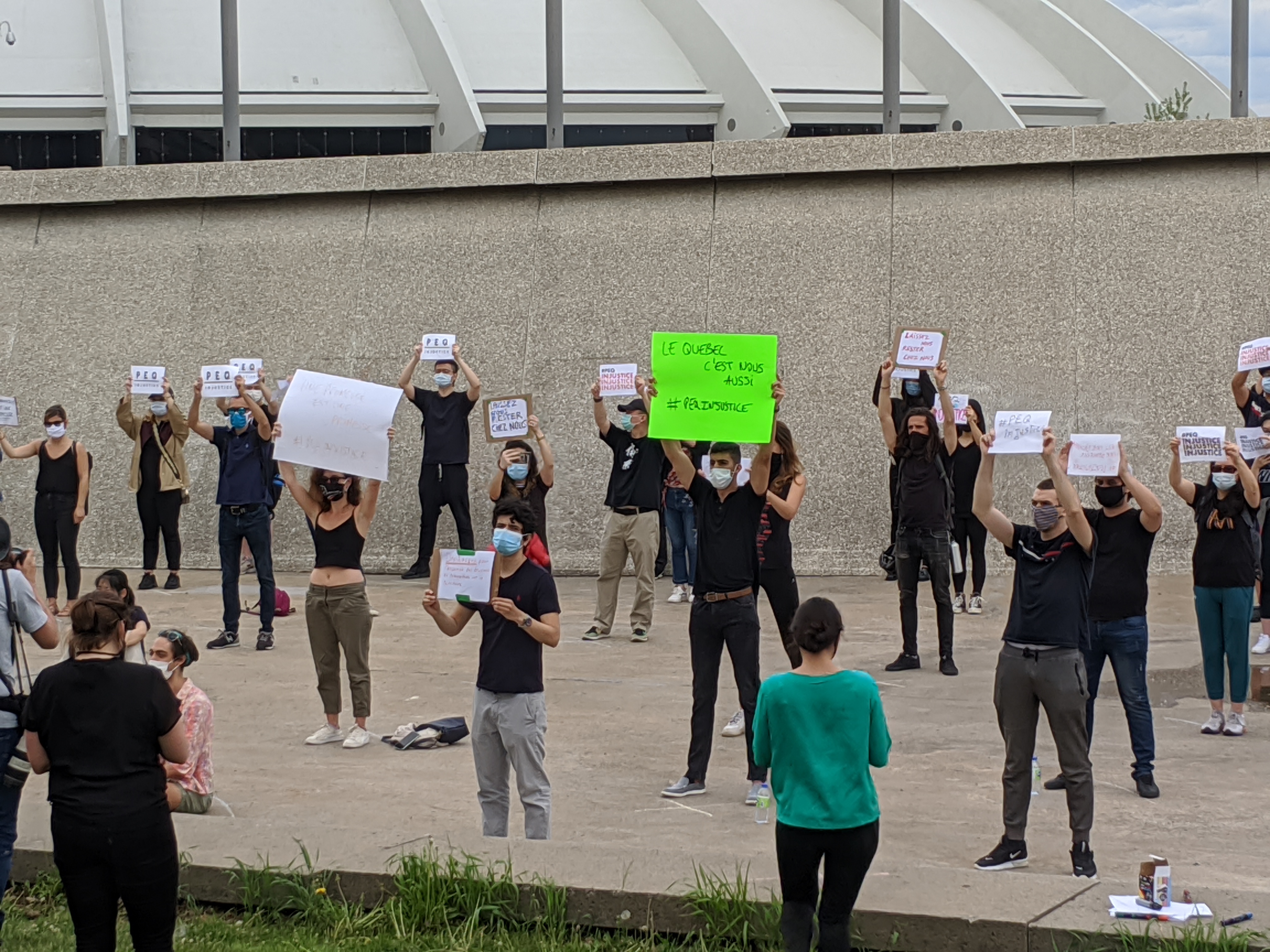 Des manifestants montrent des affiches dénonçant la réforme du PEQ, devant le Stade olympique.