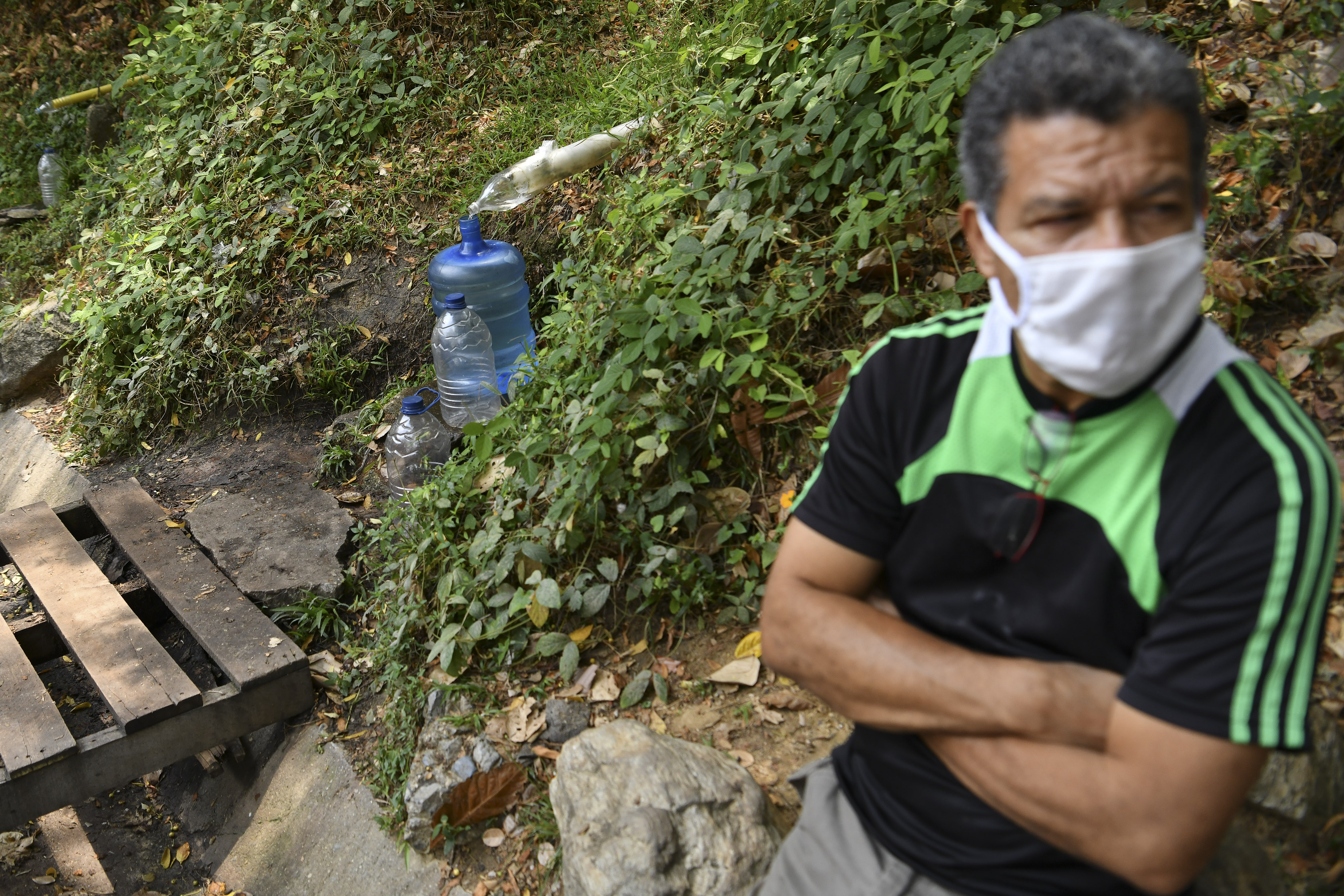 Un homme attend que de l'eau de source remplisse une bouteille, au Vénézuéla.