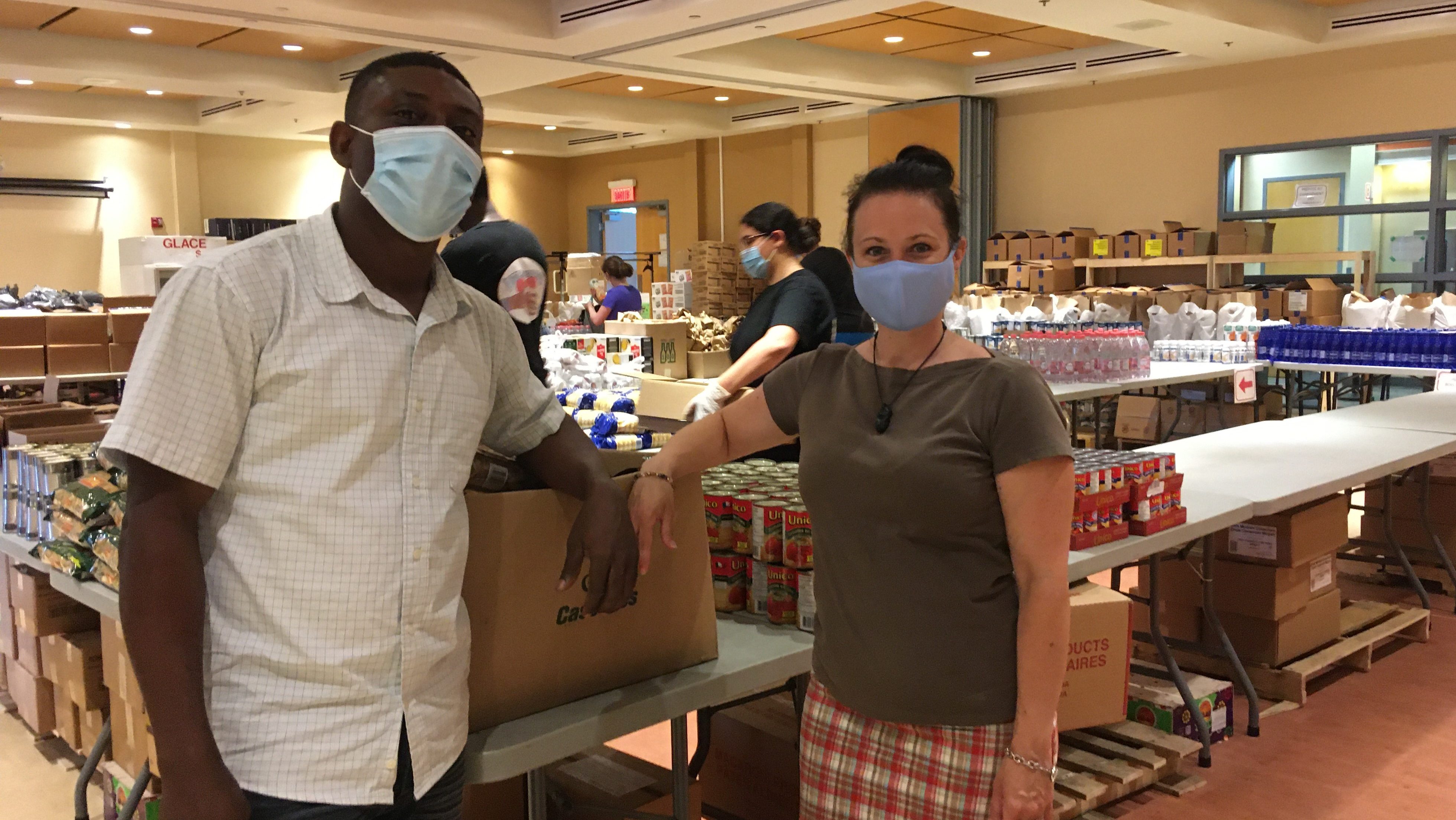 Jean Peniarold Petit Homme et Sonia Longpré-Marcoux devant des boîtes de denrées pour l'aide alimentaire.