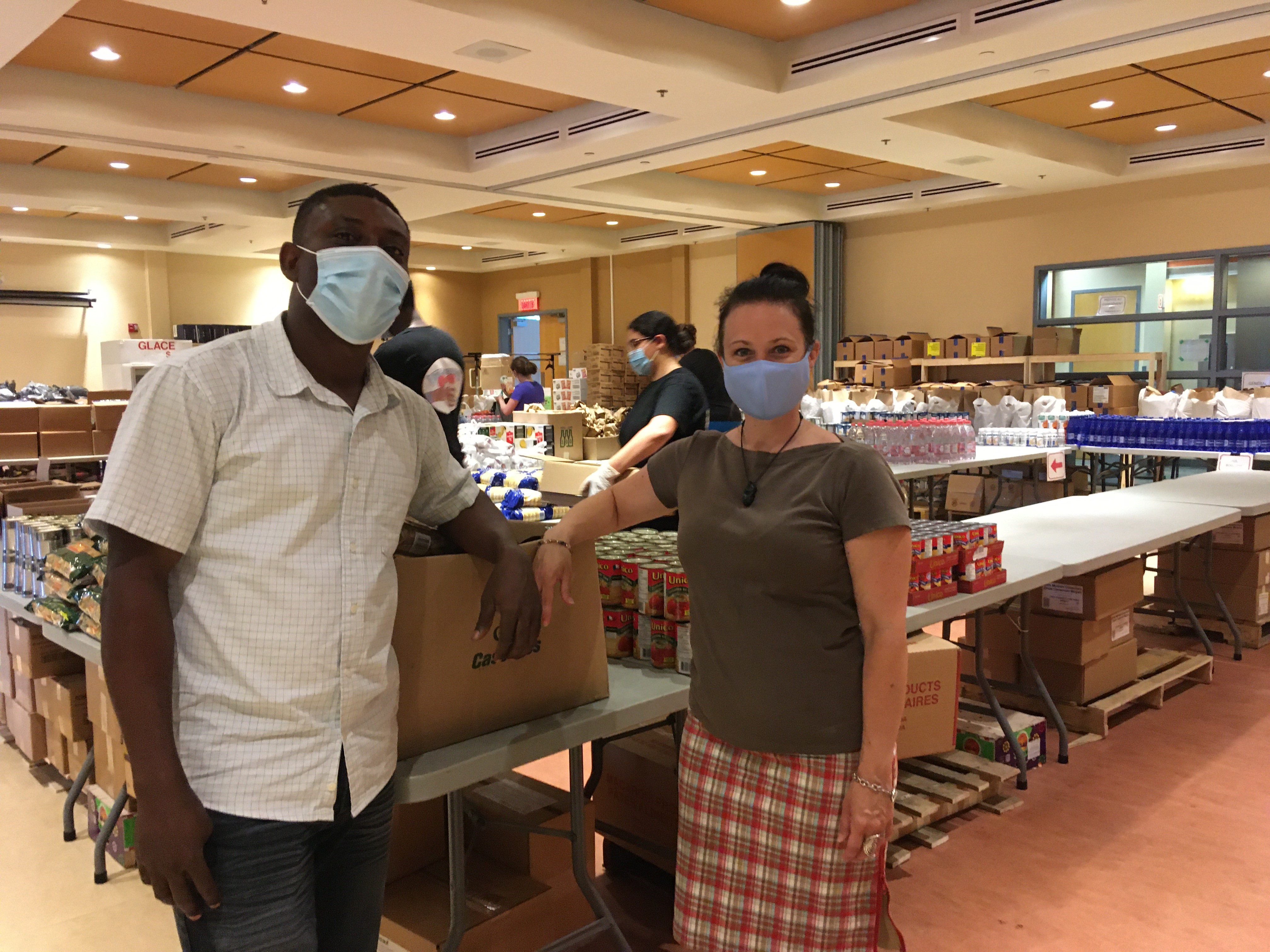 Jean Peniarold Petit Homme et Sonia Longpré-Marcoux devant des boîtes de denrées pour l'aide alimentaire.