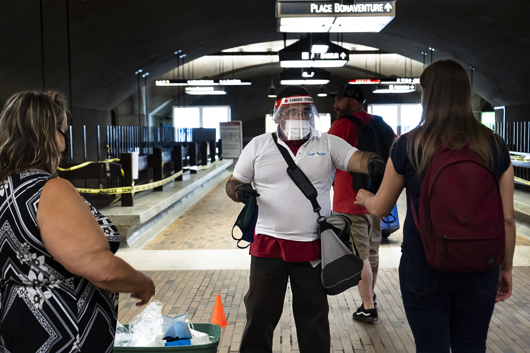 Des bénévoles distribuent des masques fournis par la STM dans une station de métro.