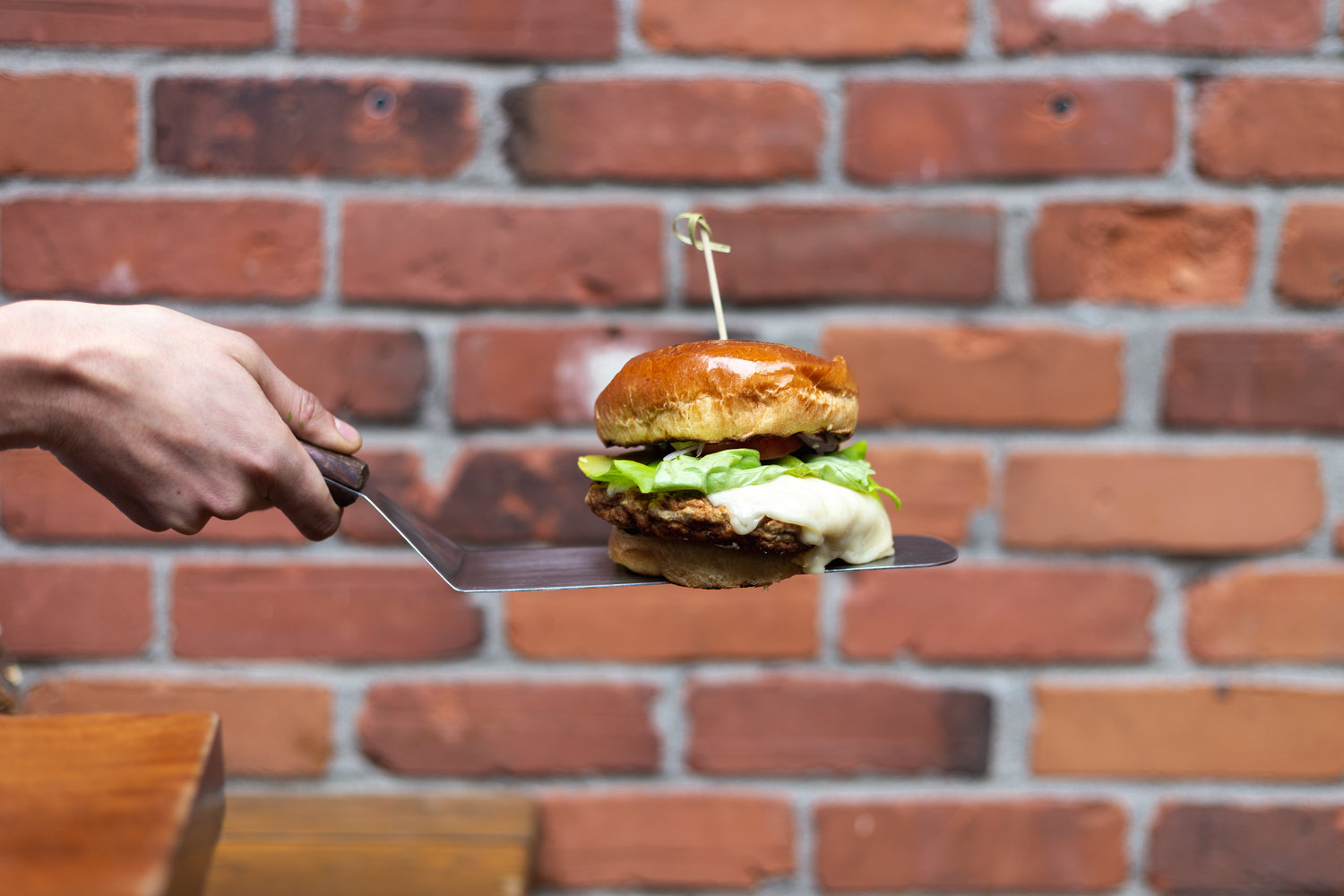 Main tenant une spatule contenant un burger