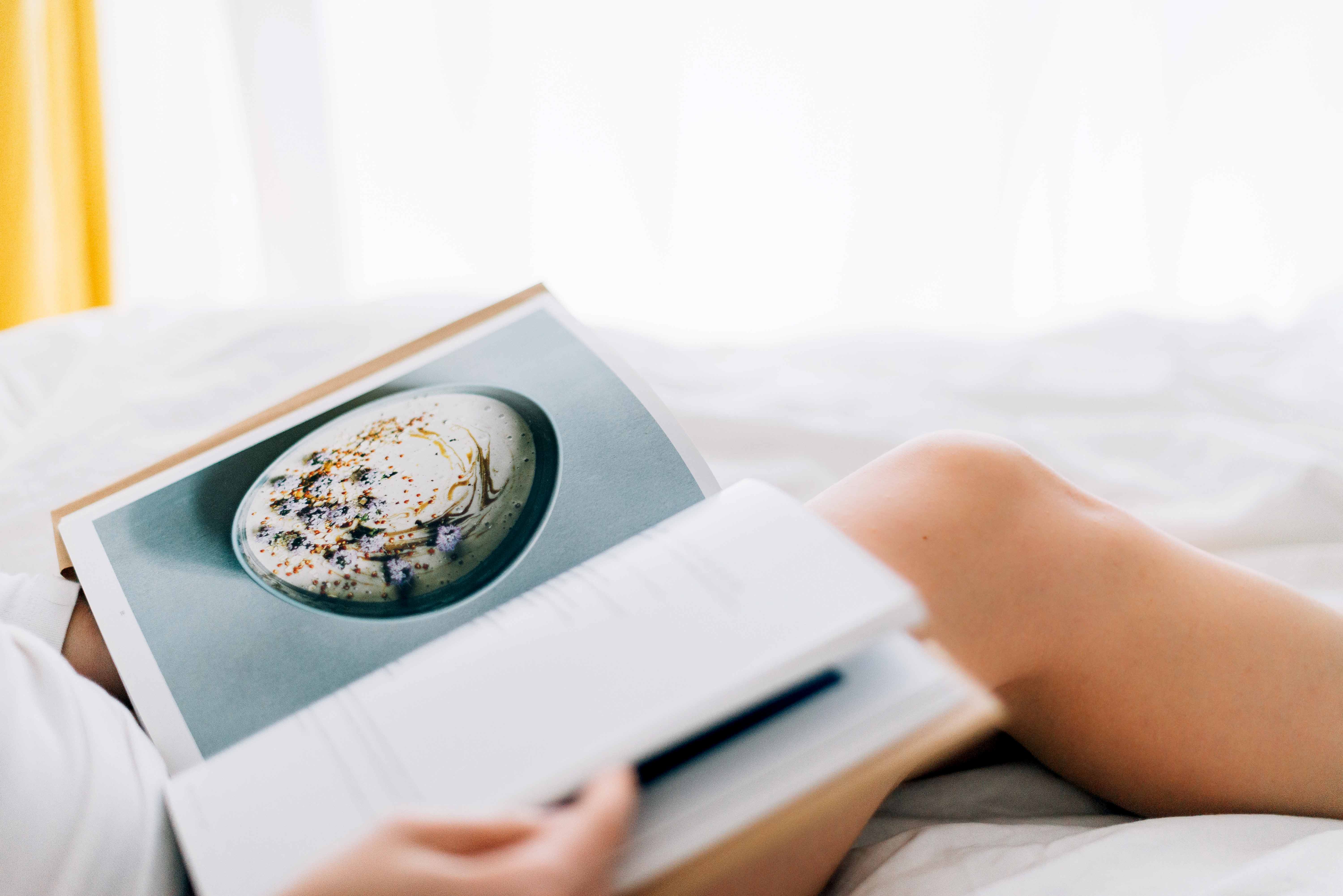 Livre de recettes déposé sur les genoux dénudés d'une jeune femme