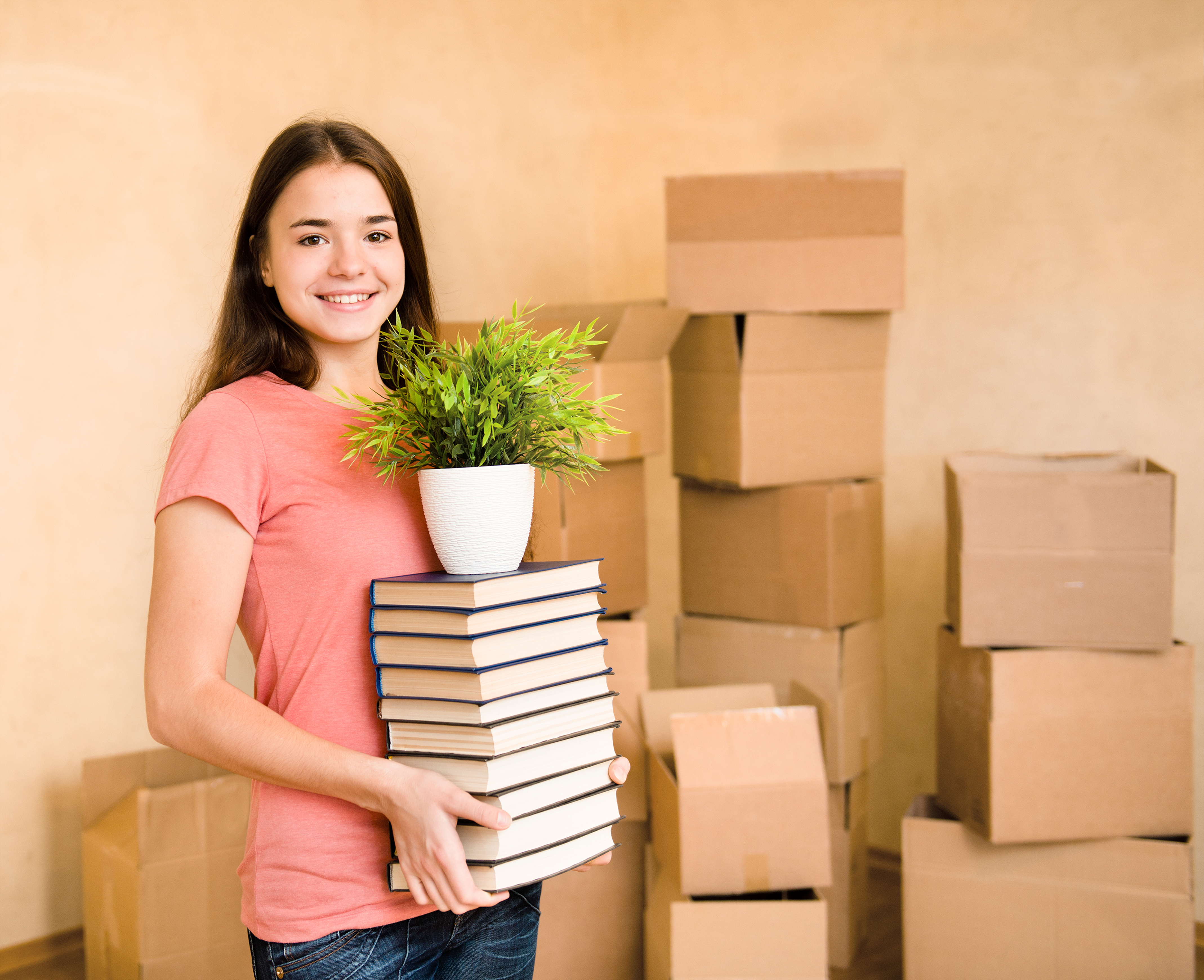 Jeune femme déménagement au collège, tenant des livres et des plantes