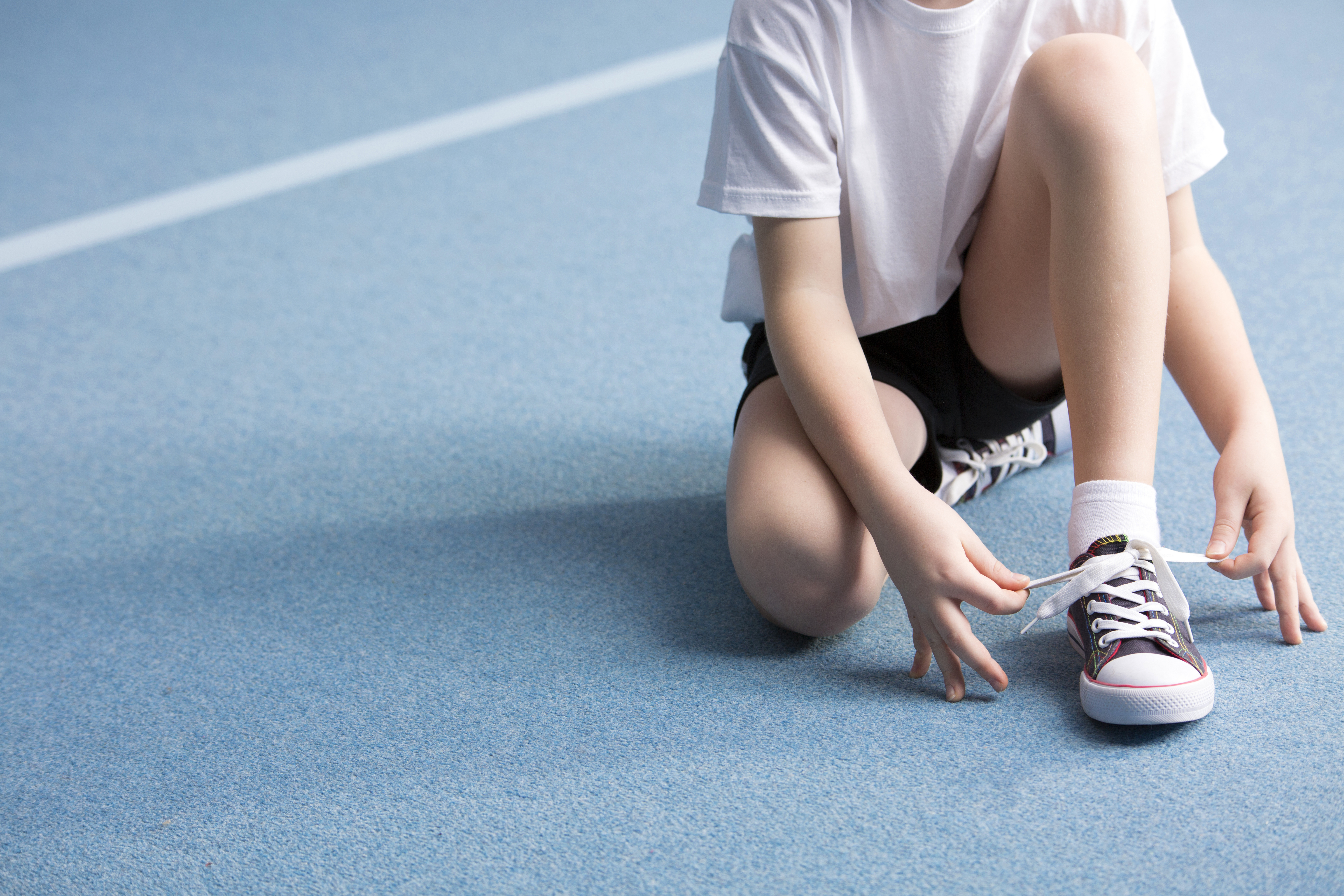 Adolescent attachant son lacet d'espadrille