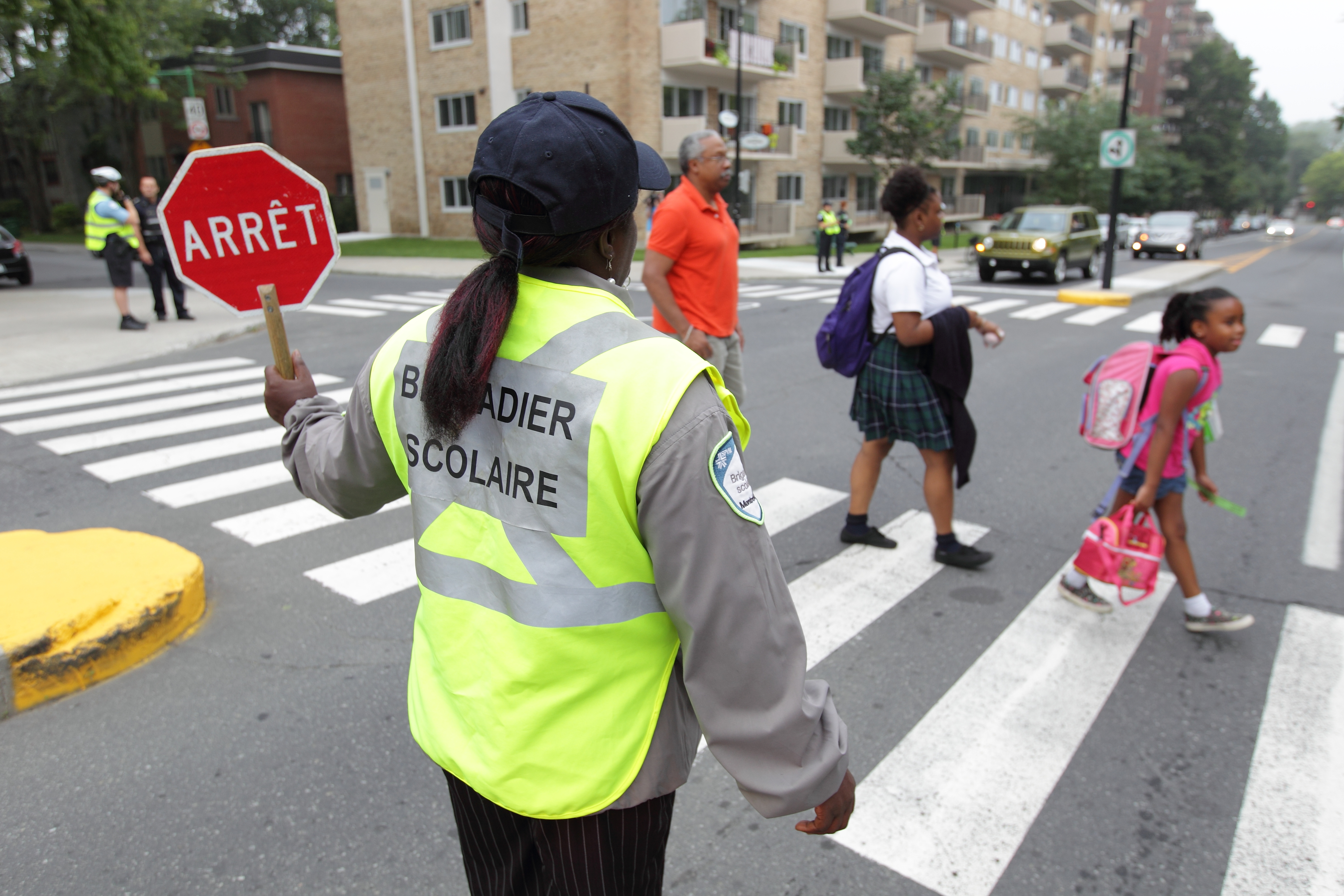 Un brigadier accompagne des enfants à un passage piéton.