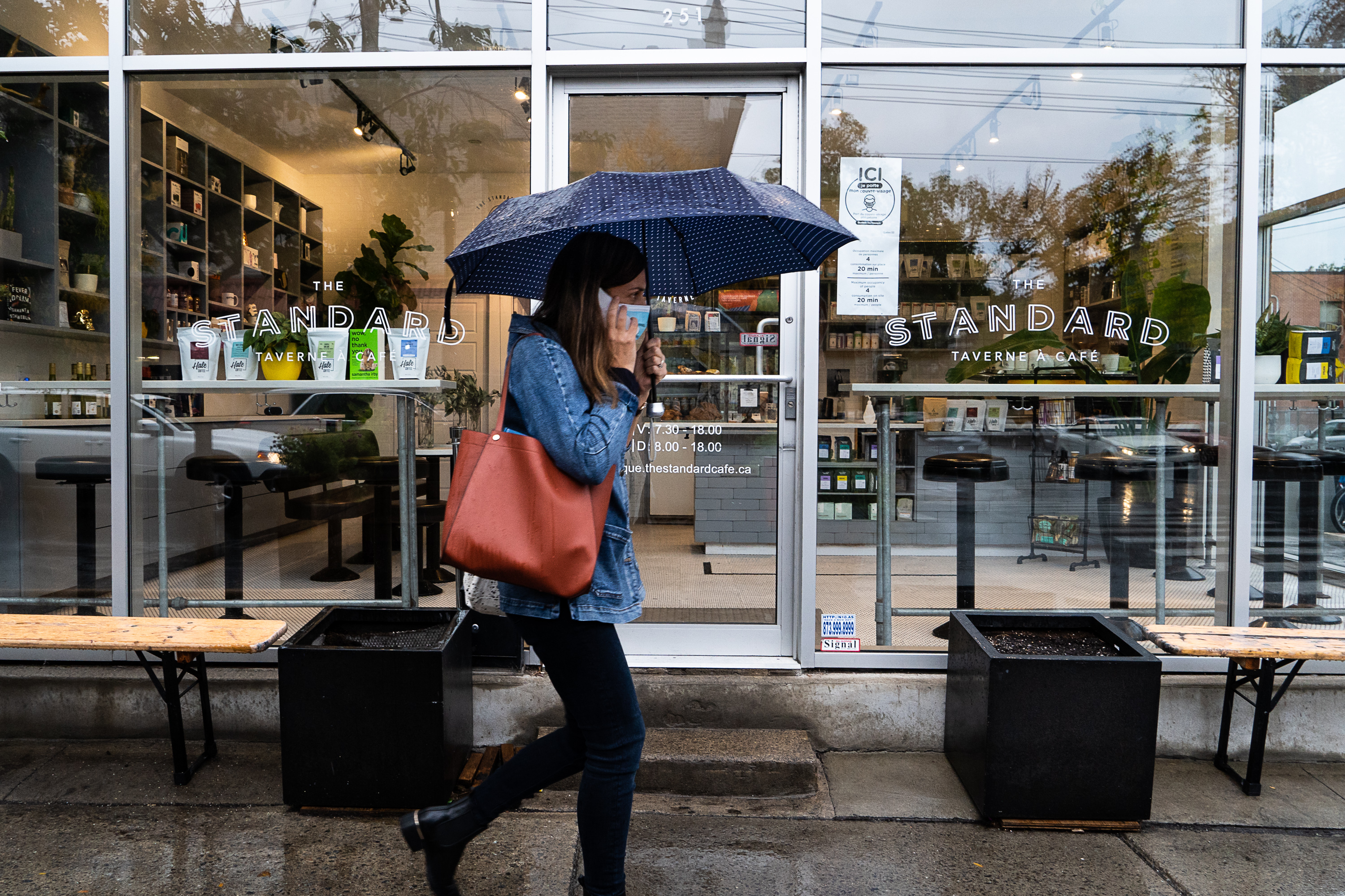 Une dame porte le masque devant un café à Montréal.