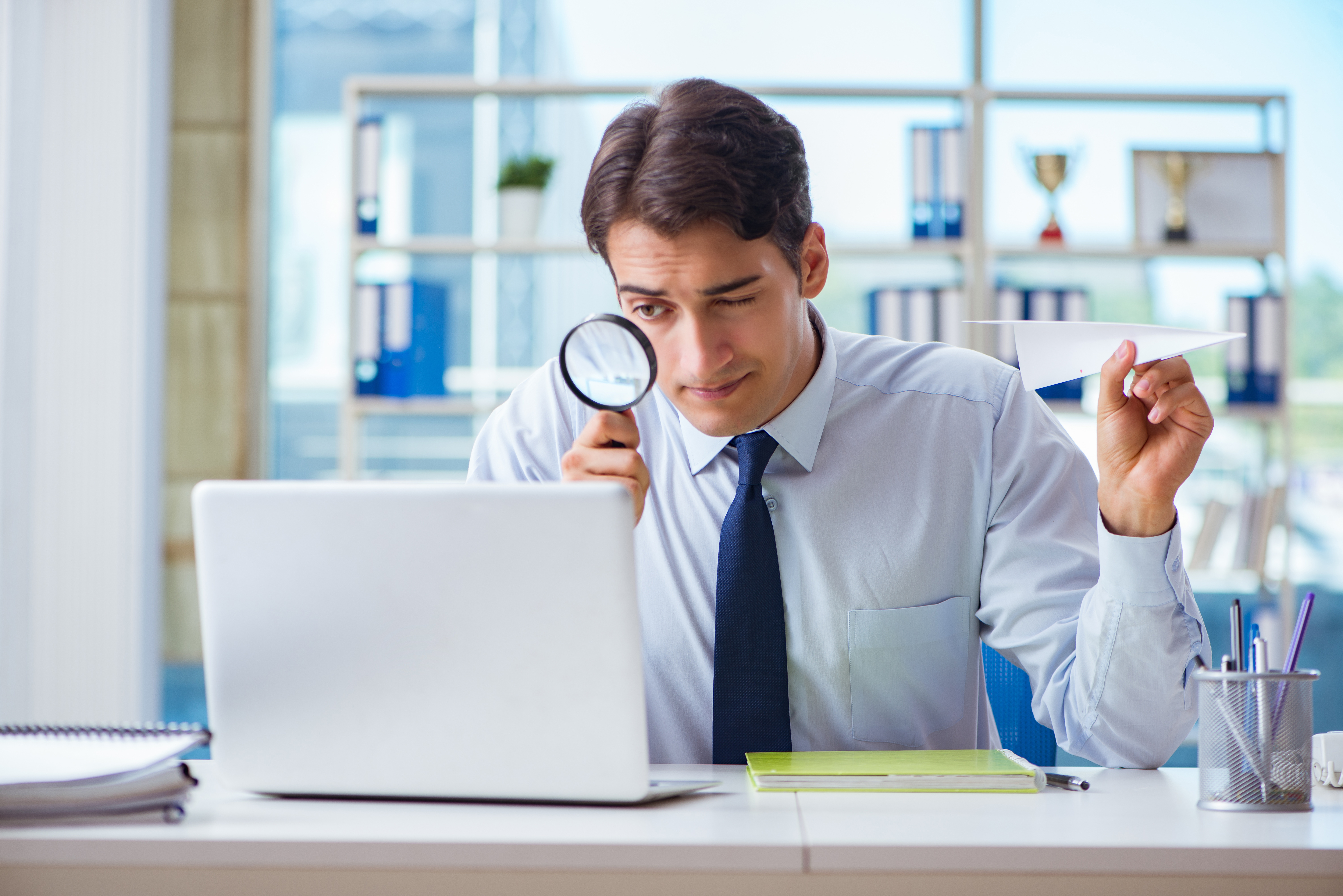 Businessman with magnifying glass and paper plane