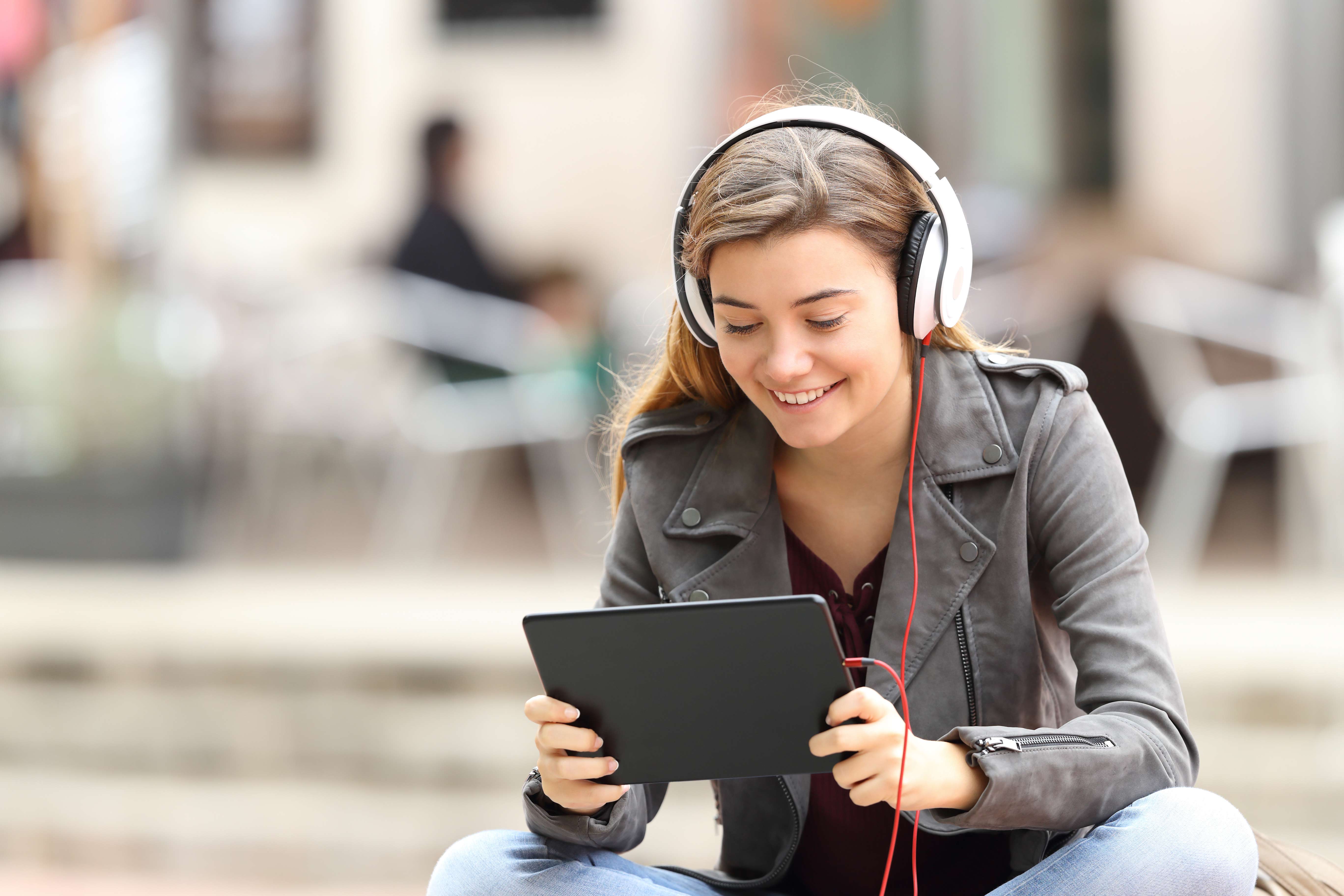 Jeune fille avec des écouteurs regarde sa tablette électronique