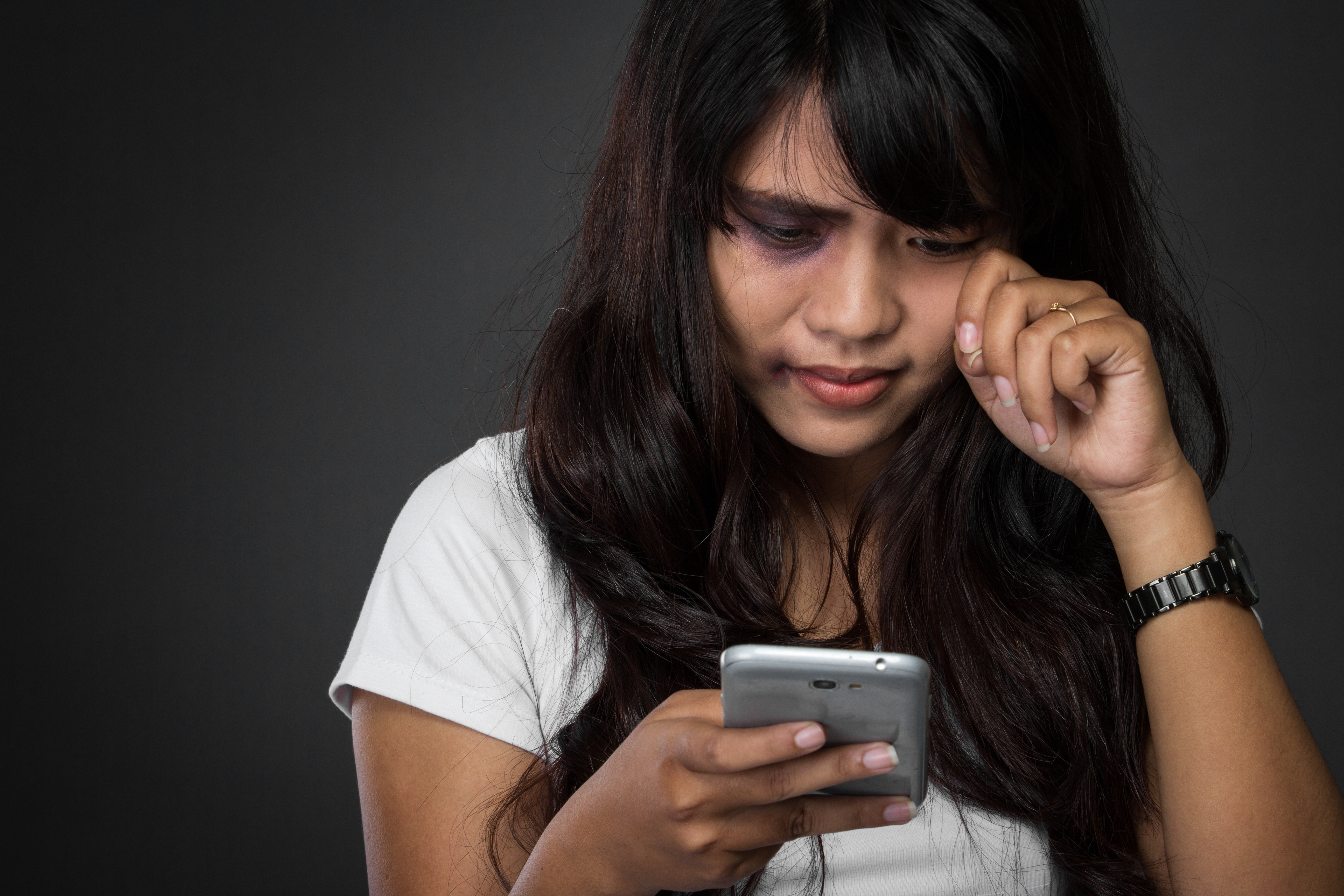 une femme regarde son téléphone et pleure