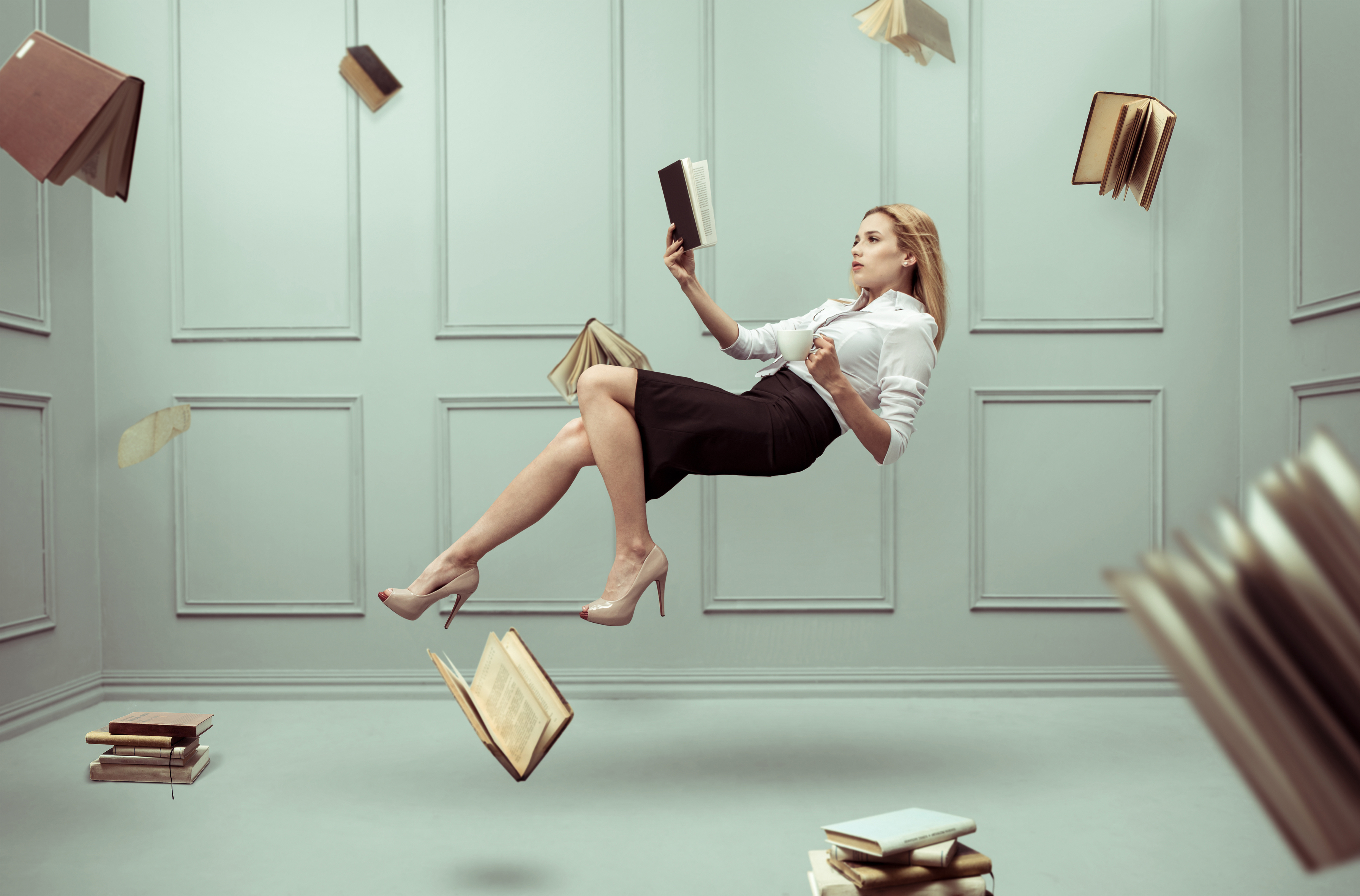 A relaxed woman levitates in a room full of flying books