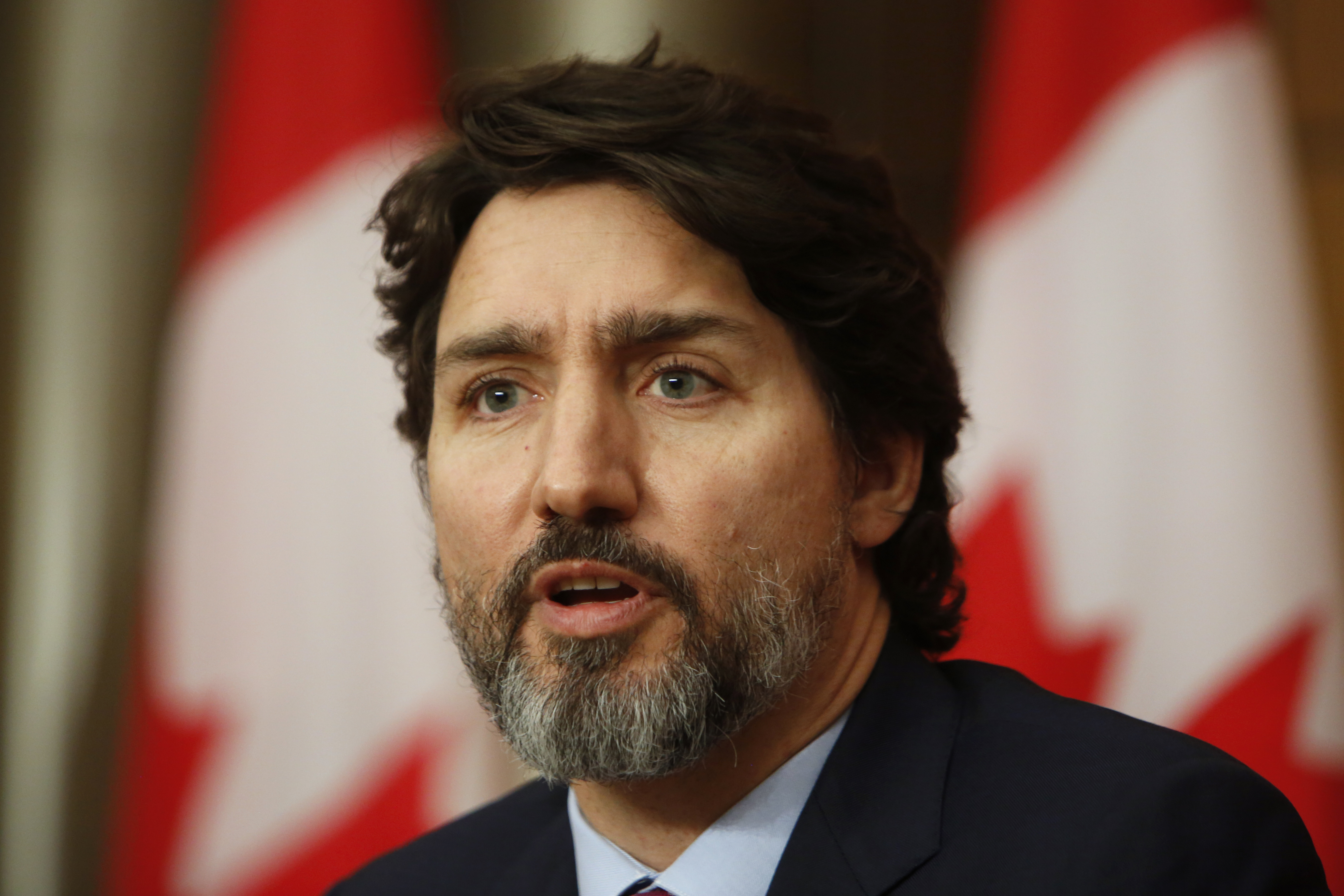 Justin Trudeau, premier ministre du Canada, devant des drapeaux canadiens.