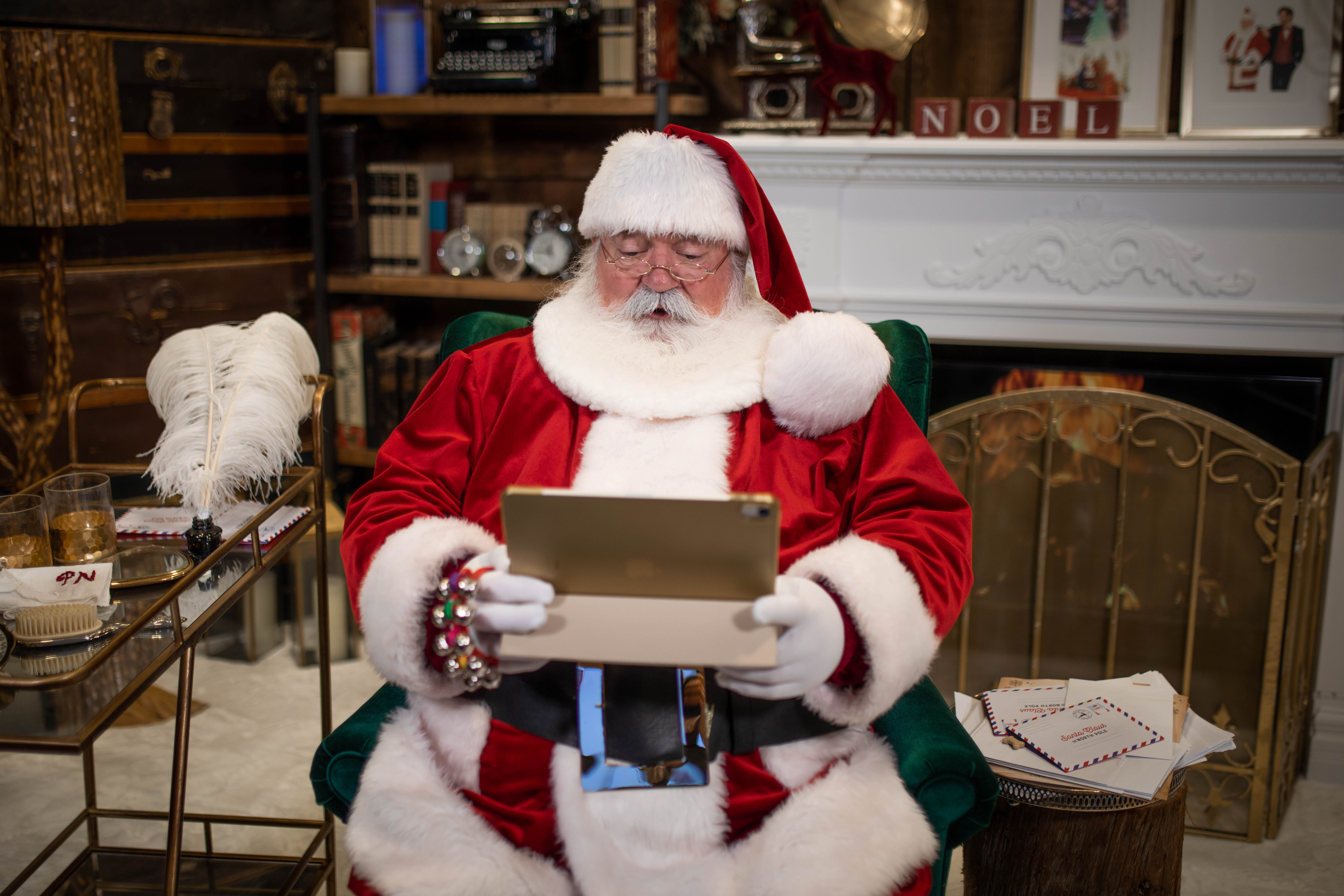 Le père Noël tenant une tablette électronique dans son salon au Pôle-Nord.