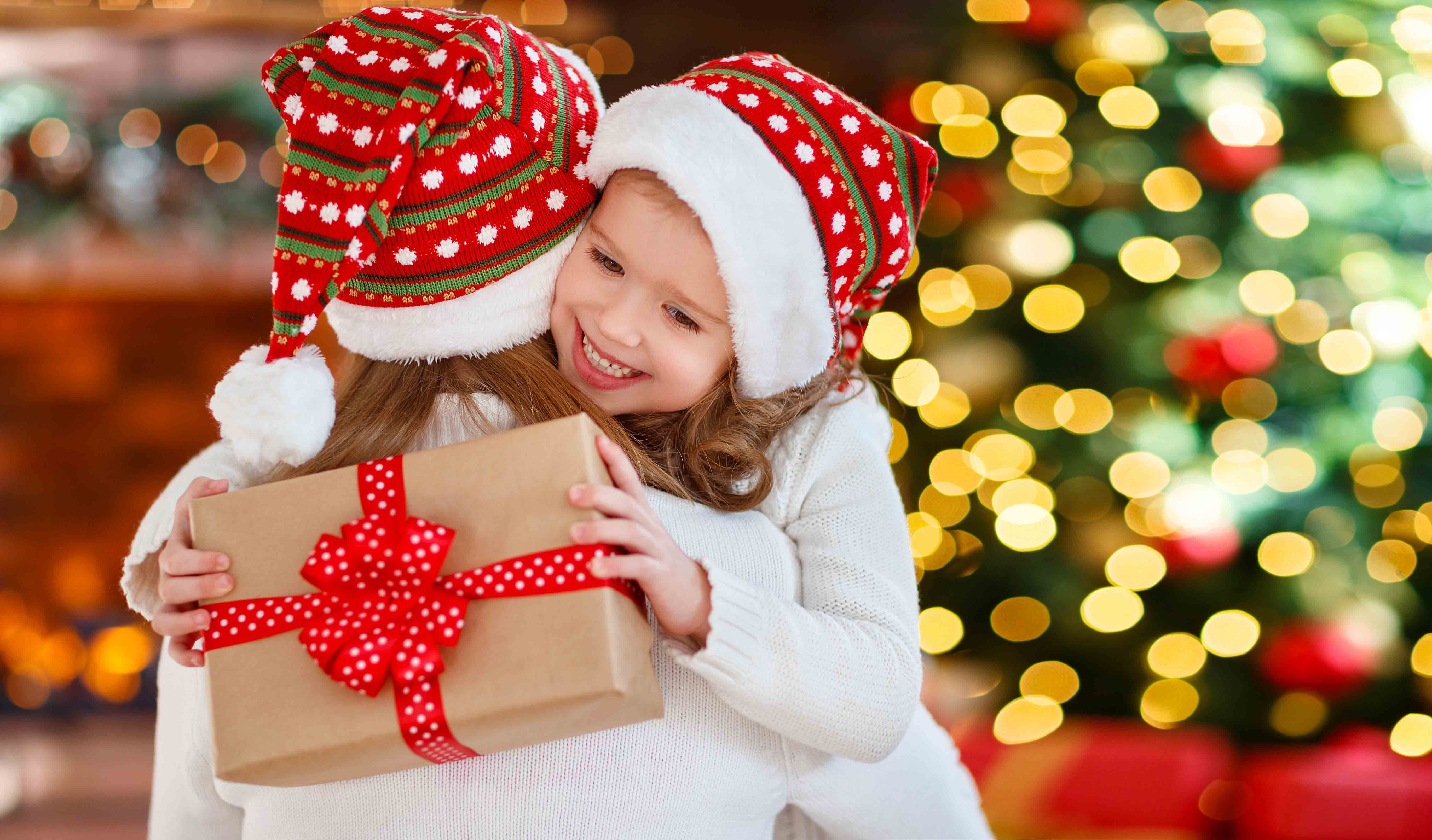 Heureuse famille mère et fille donnant un cadeau de Noël et s'embrassant