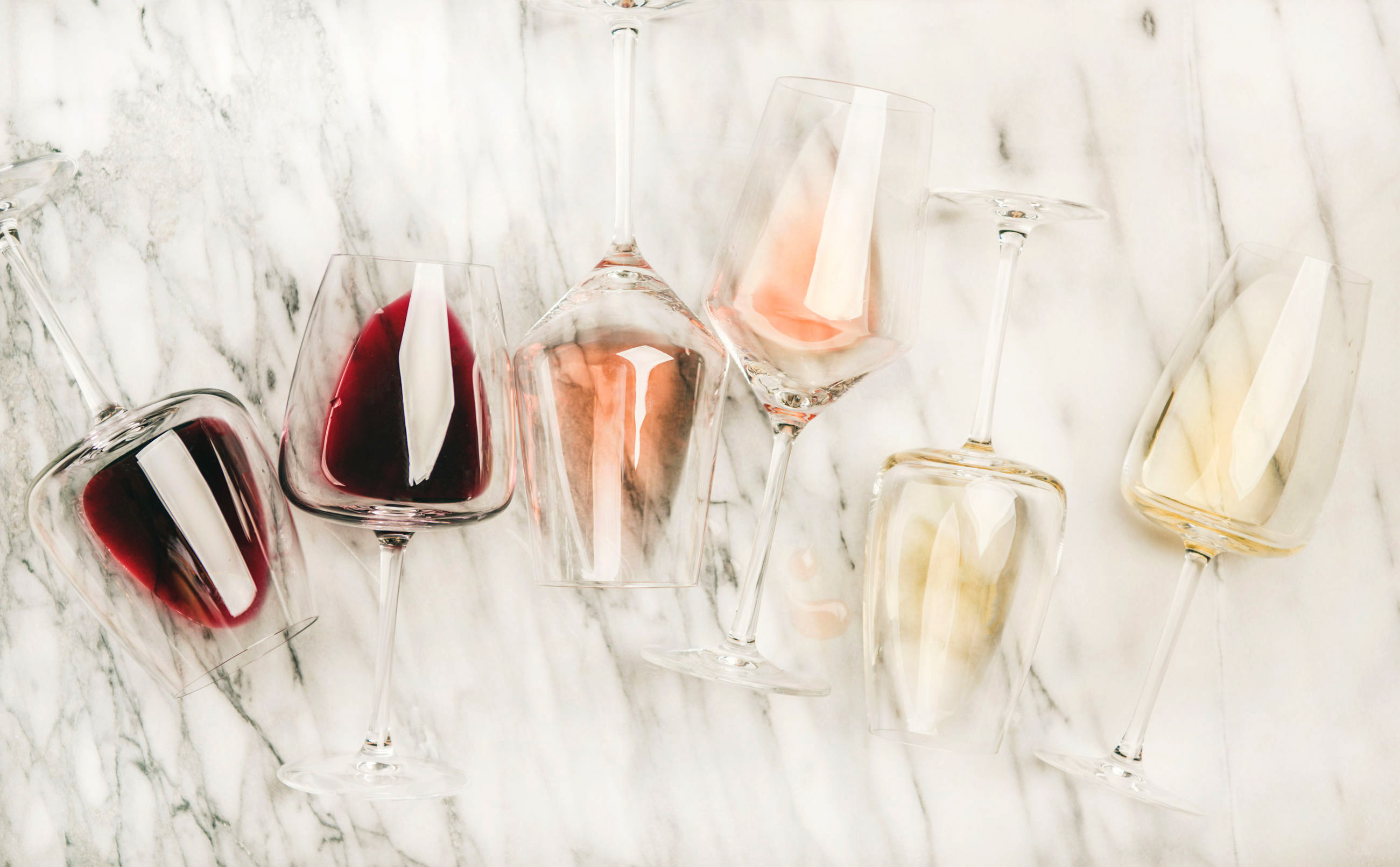 Coupes de vin rouge, blanc et rosé sur fond de marbre.