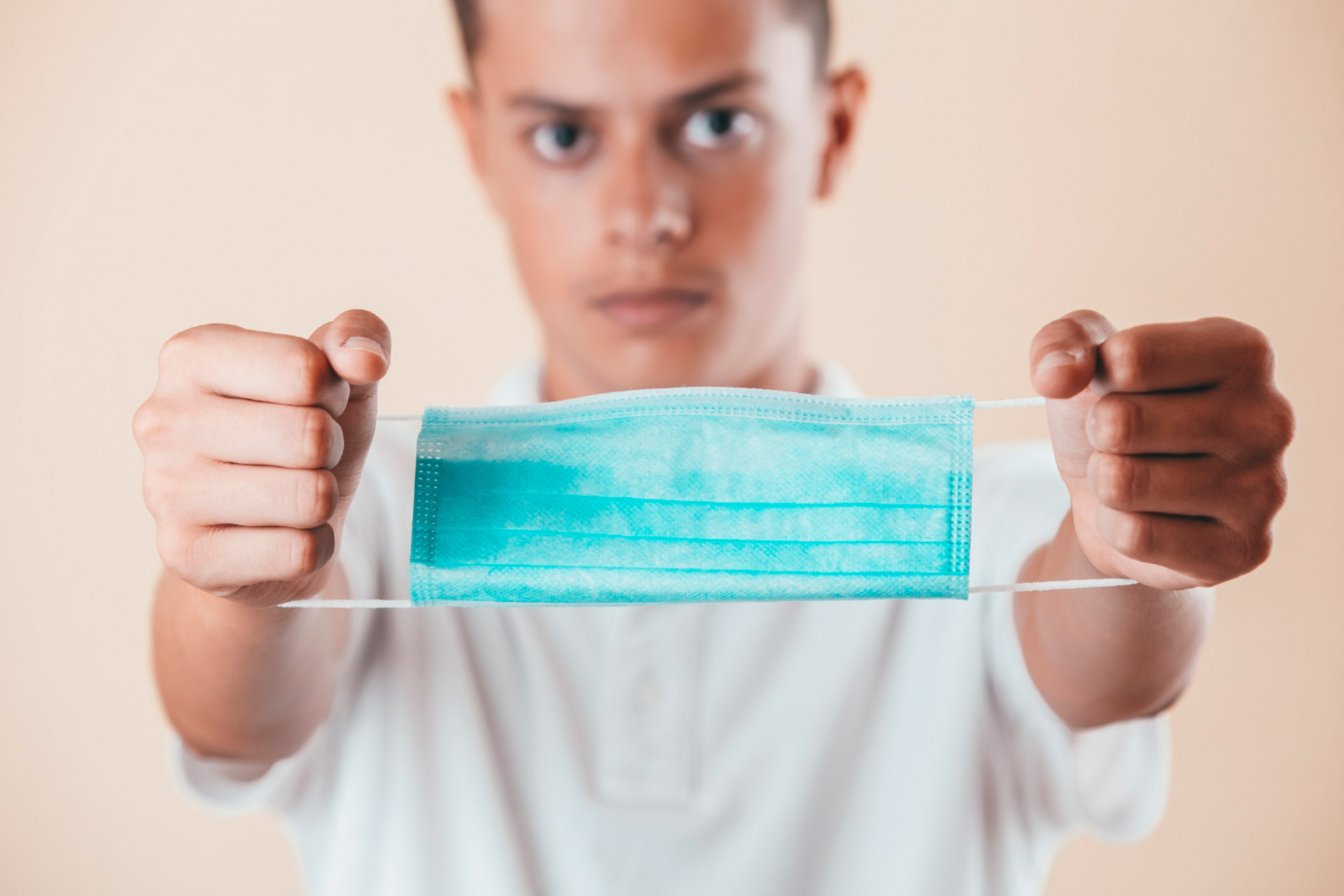 Jeune homme montrant un masque pour se protéger de la COVID-19