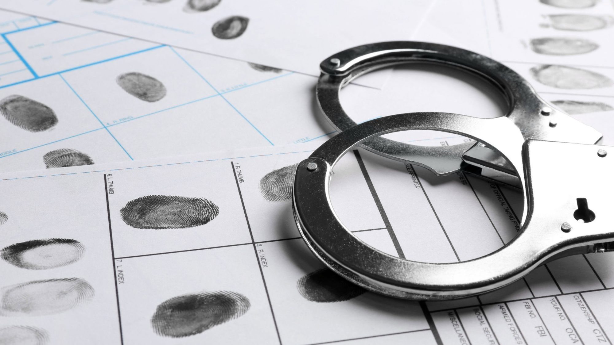 des menottes et des empreintes digitales symbolisant une personne avec un casier judiciaire.