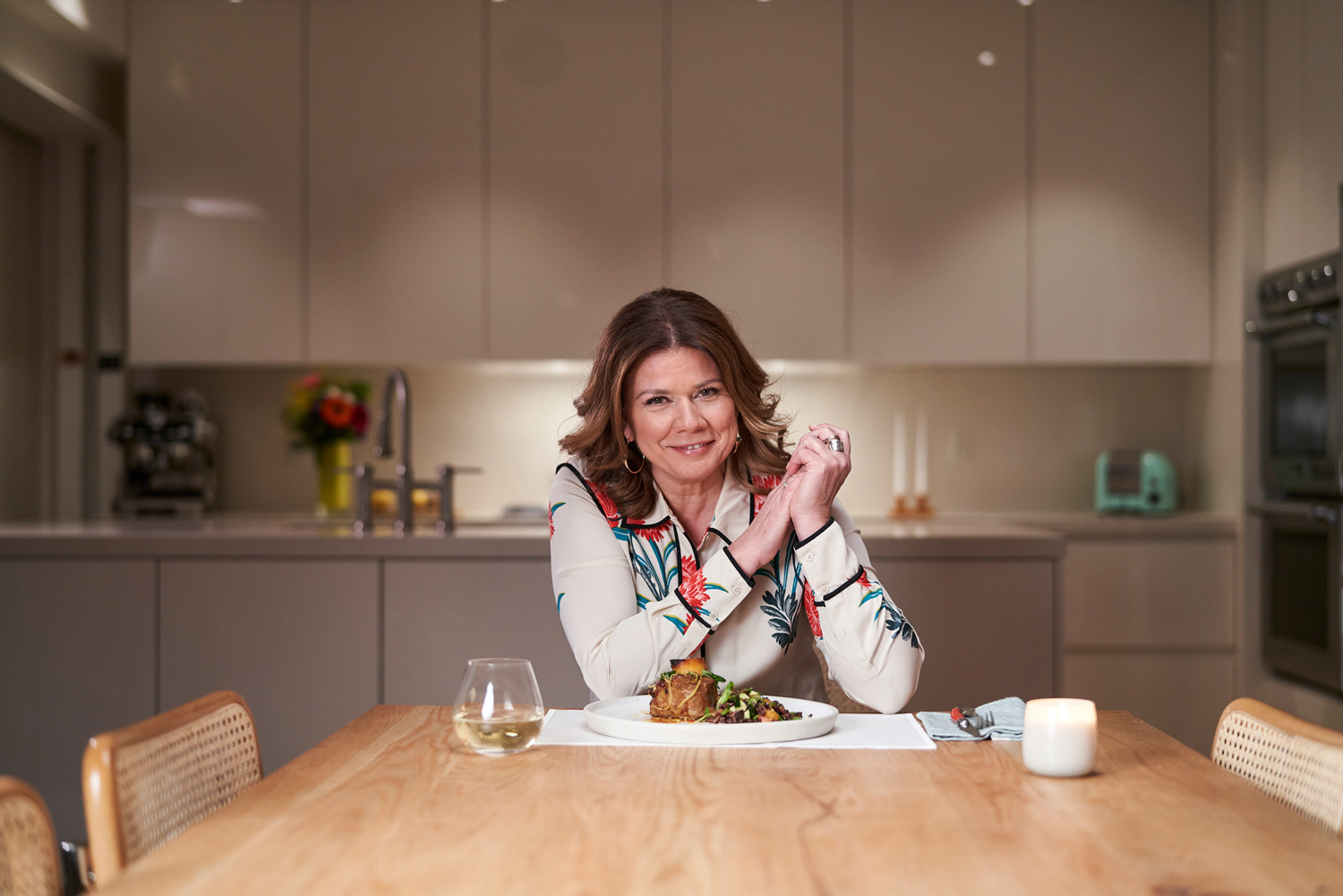 La comédienne et animatrice Marina Orsini assise à une table face à un plat cuisiné.