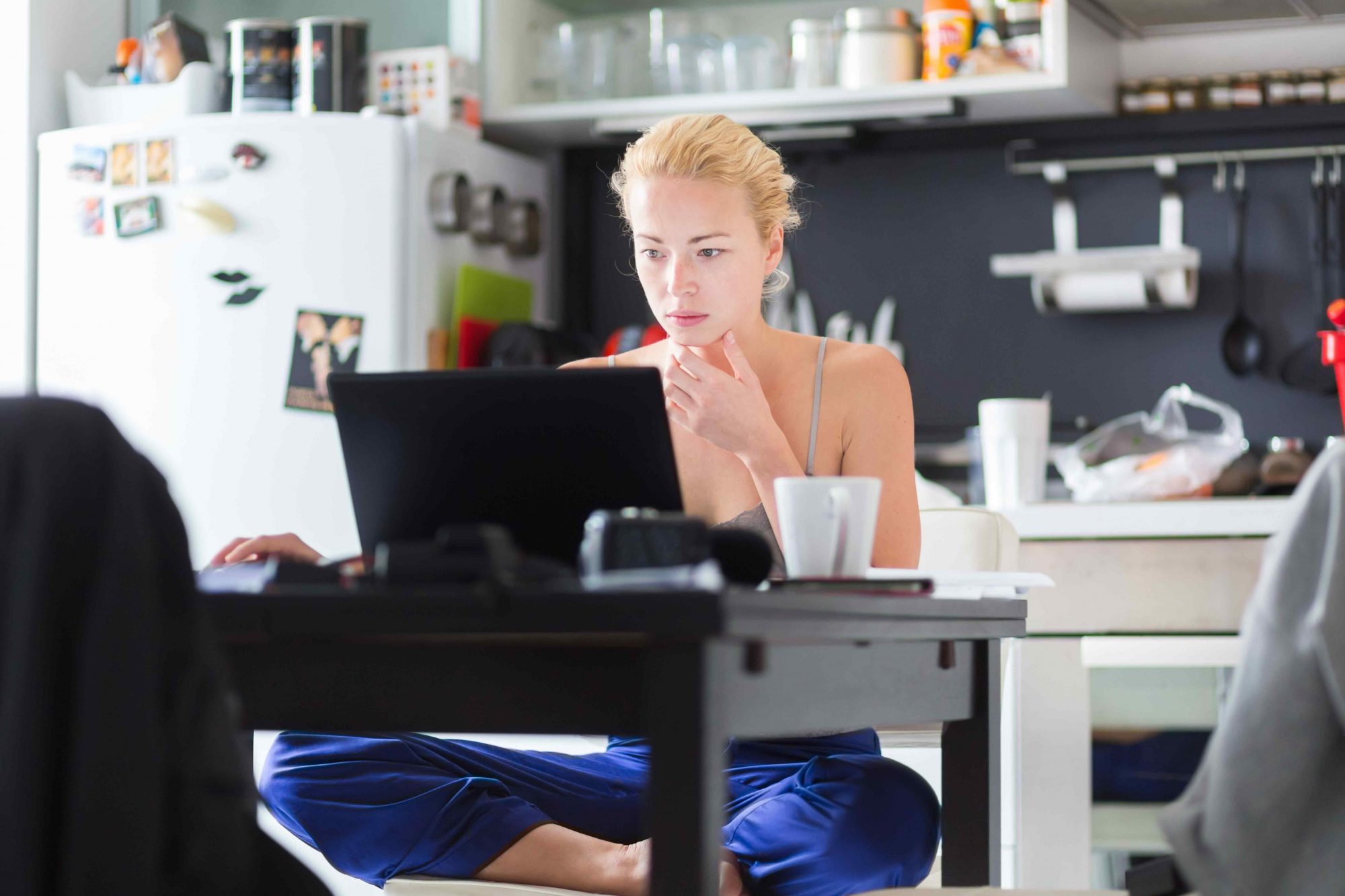 Pigiste Femme dans ses vêtements d'accueil occasionnel de travail remotly de sa table à manger le matin. Accueil cuisine dans l'arrière-plan.