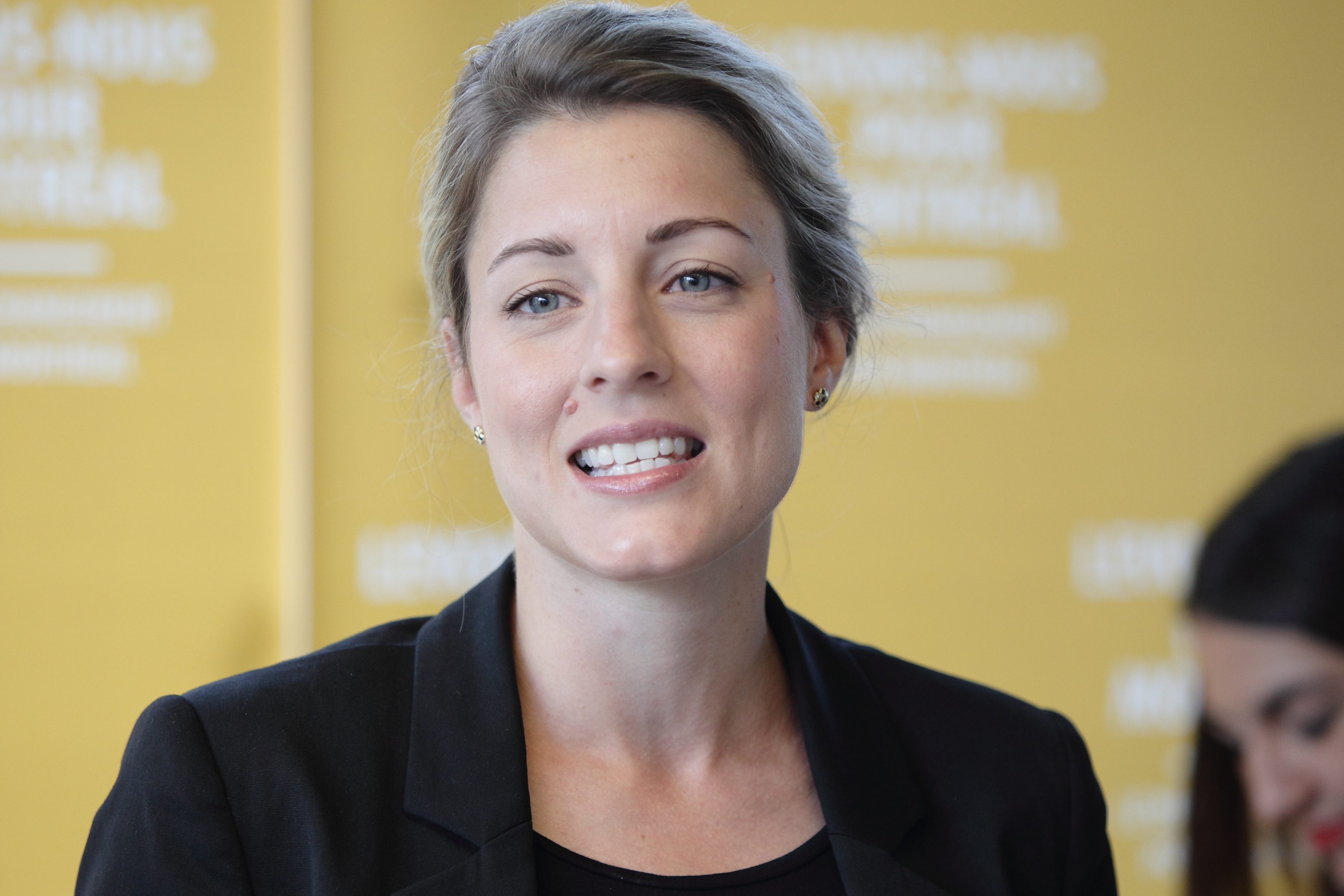 Mélanie Joly devant une affiche jaune du parti Vrai changement pour Montréal