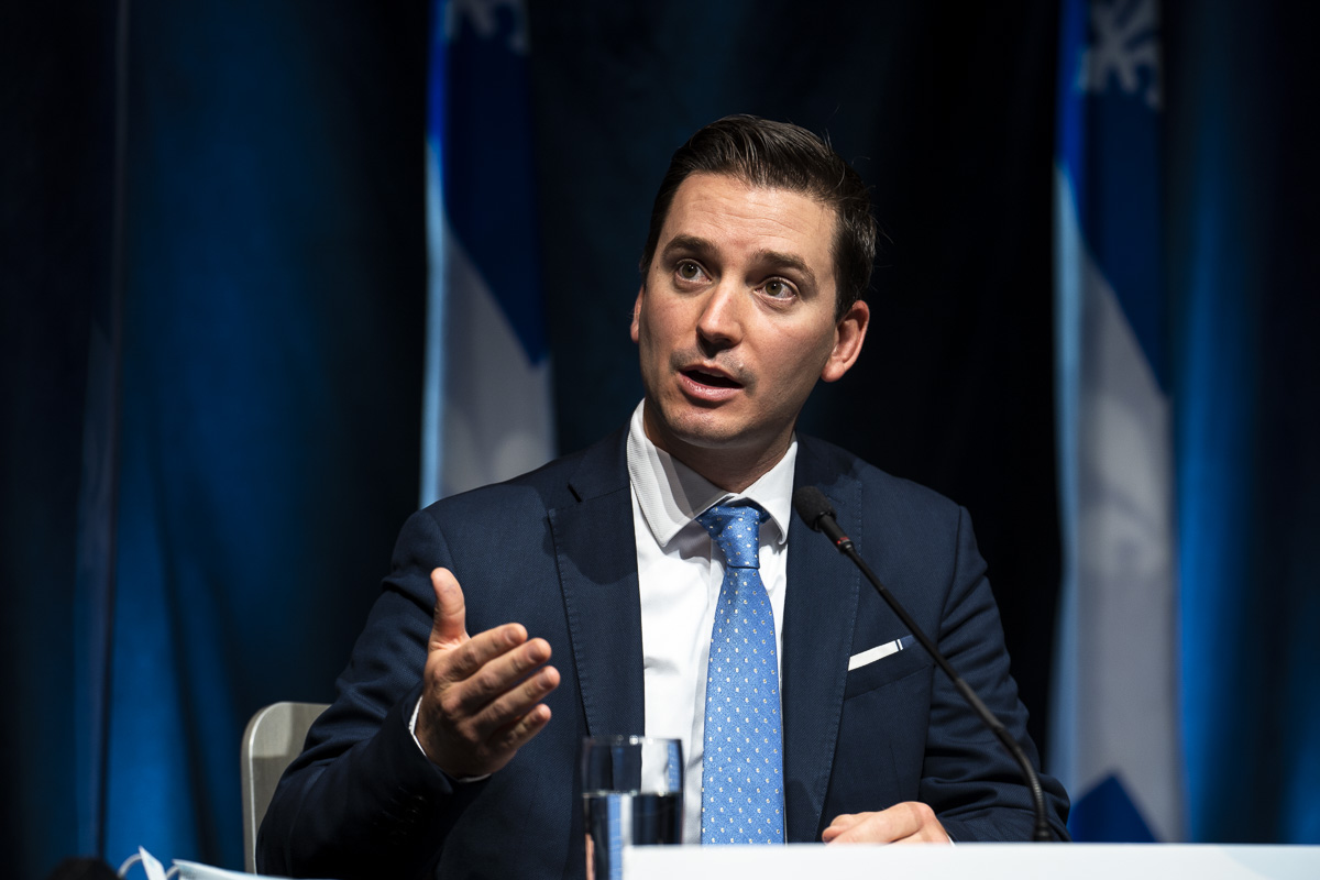 Le ministre responsable de la Langue française, Simon Jolin-Barrette, assis devant un drapeau du Québec.