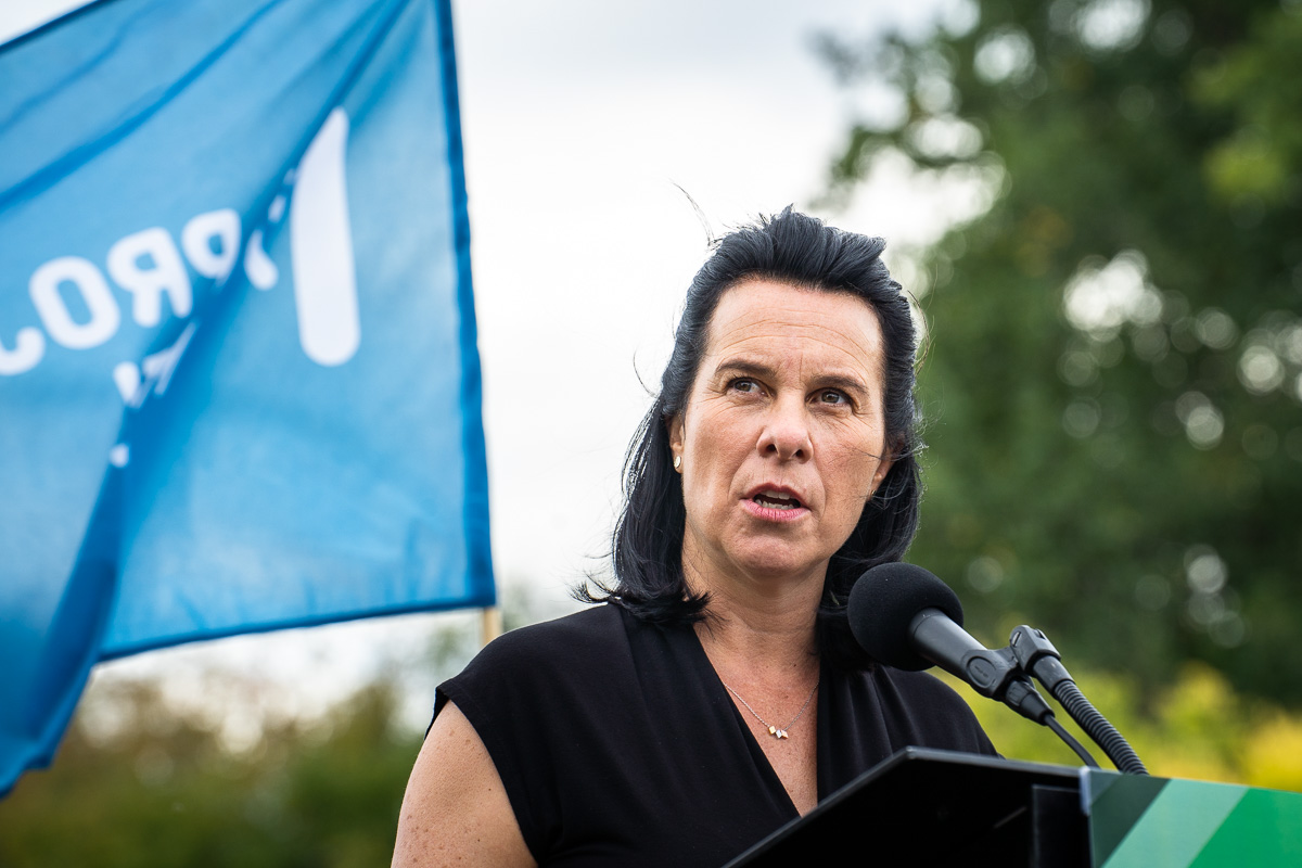 Valérie Plante devant un drapeau de Projet Montréal pendant une annonce sur le registre des loyers