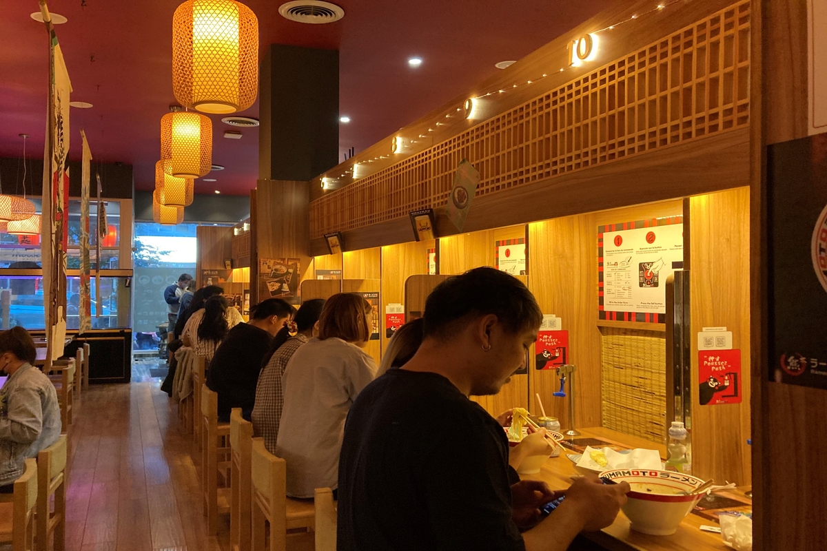 Des clients assis à un comptoir du restaurant japonais Kumamoto Ramen.