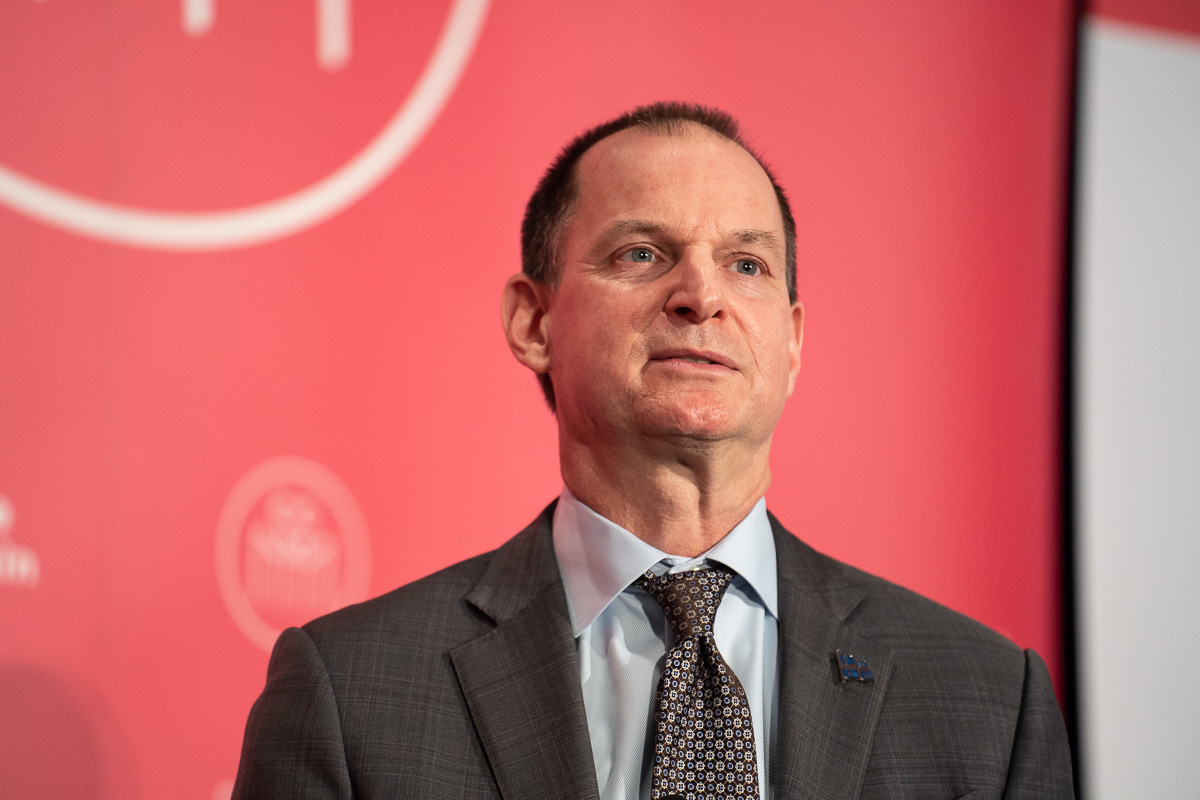 Éric Girard devant une affiche de la Chambre de Commerce du Montréal Métropolitain (CCMM)