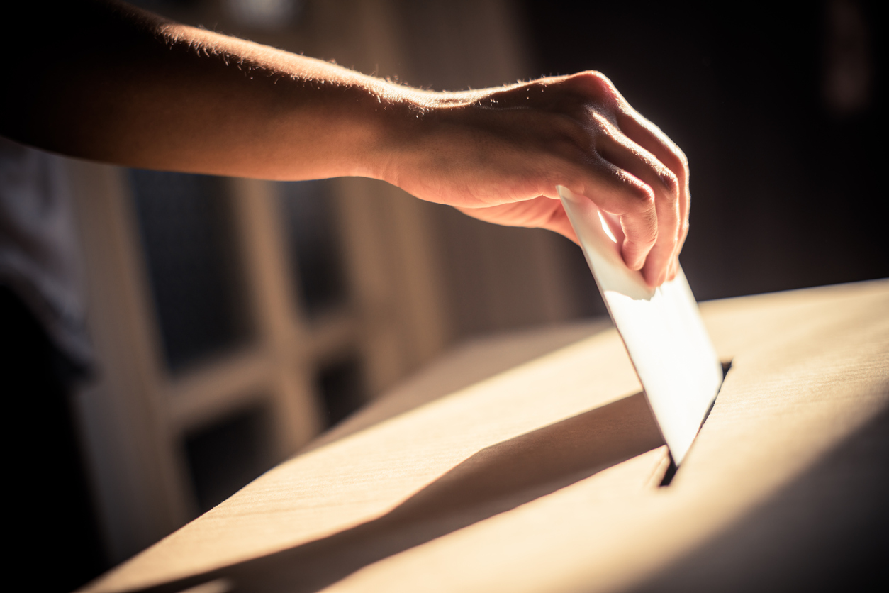 main mettant un bulletin de vote dans un urne