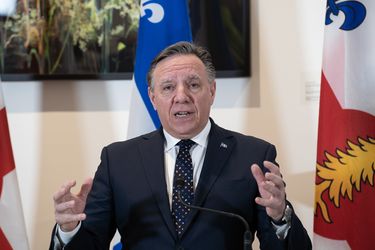 François Legault devant un drapeau du Québec à l'hôtel de ville de Montréal.