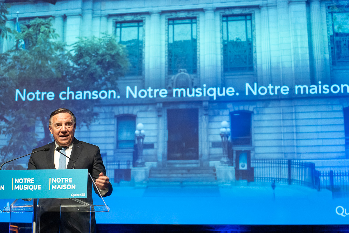 François Legault devant une image annonçant que la Bibliothèque Saint-Sulpice deviendra la Maison de la chanson et de la musique du Québec