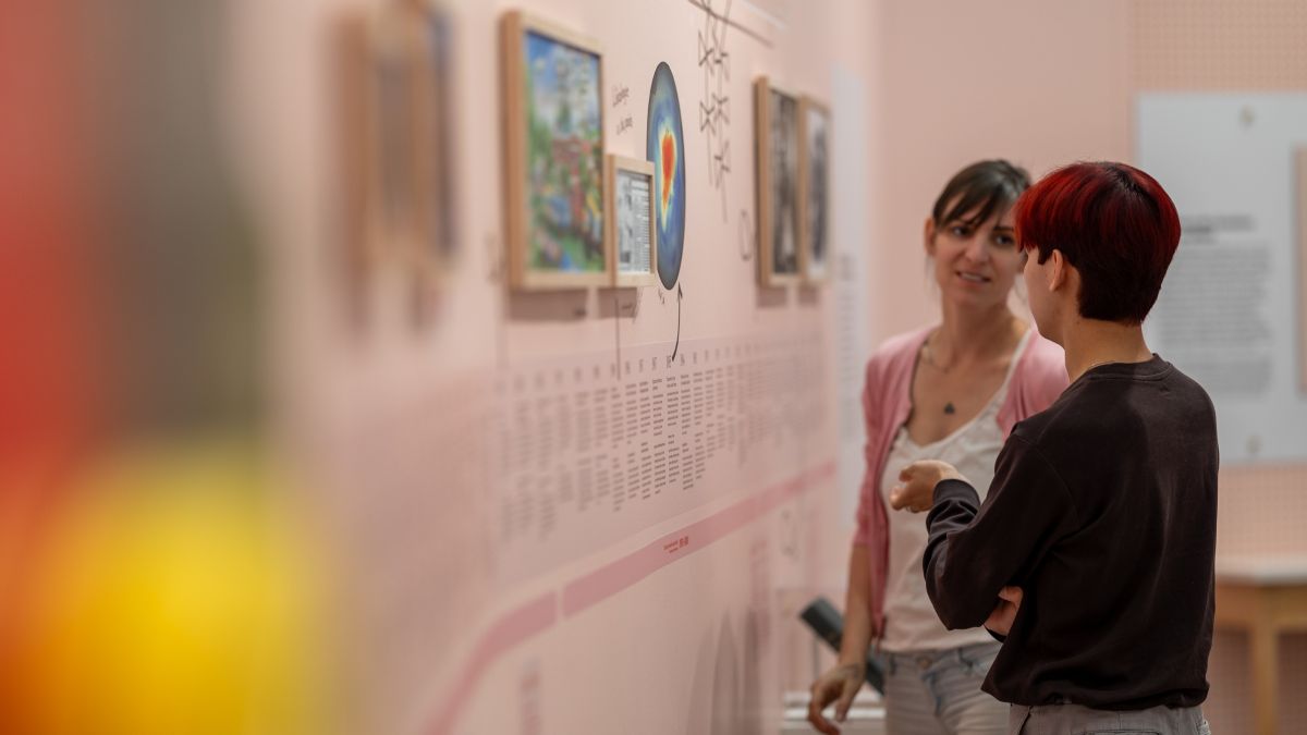 Deux adolescents discutent devant un mur d'informations de l'exposition Émolab à la Biosphère.