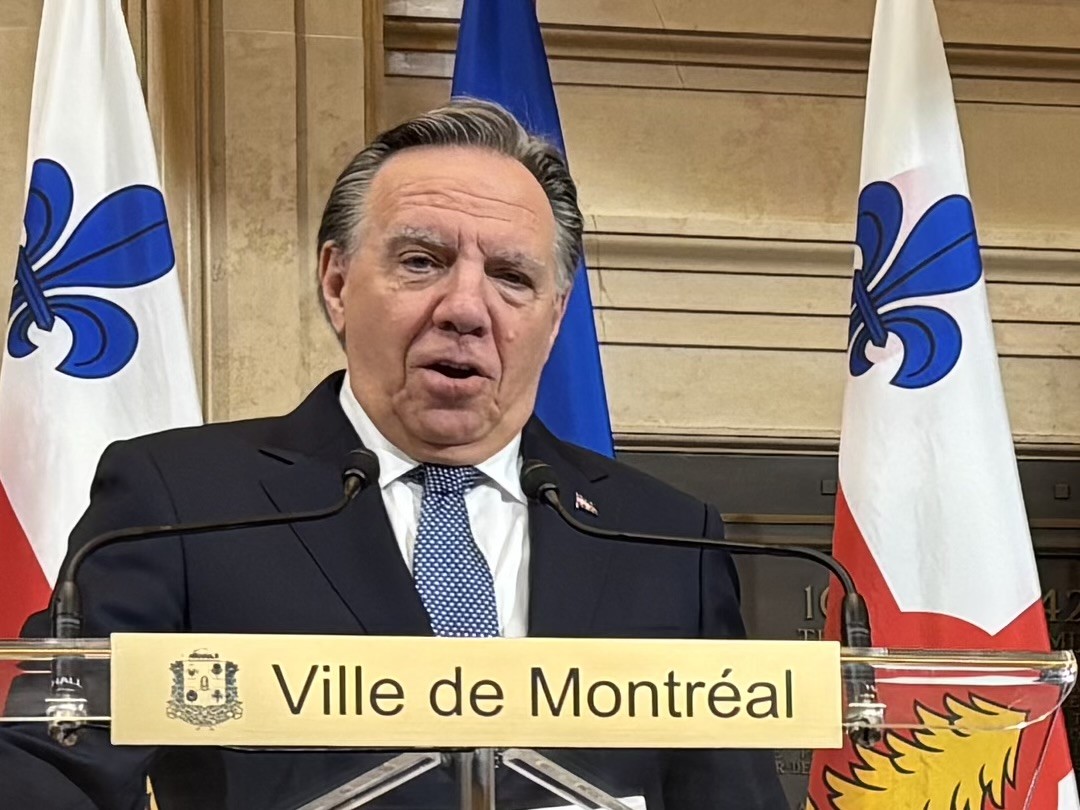 François Legault à l'hôtel de ville devant des drapeaux de Montréal et du Québec.