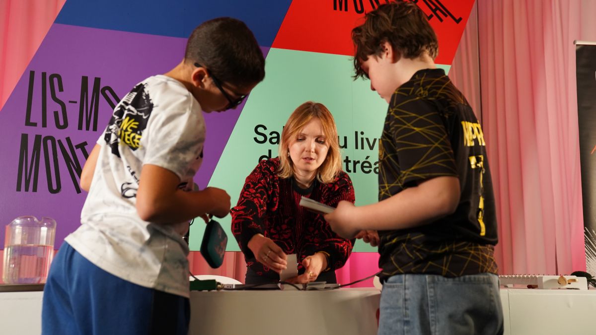 Une femme anime un atelier pour deux enfants au Salon du livre de Montréal.
