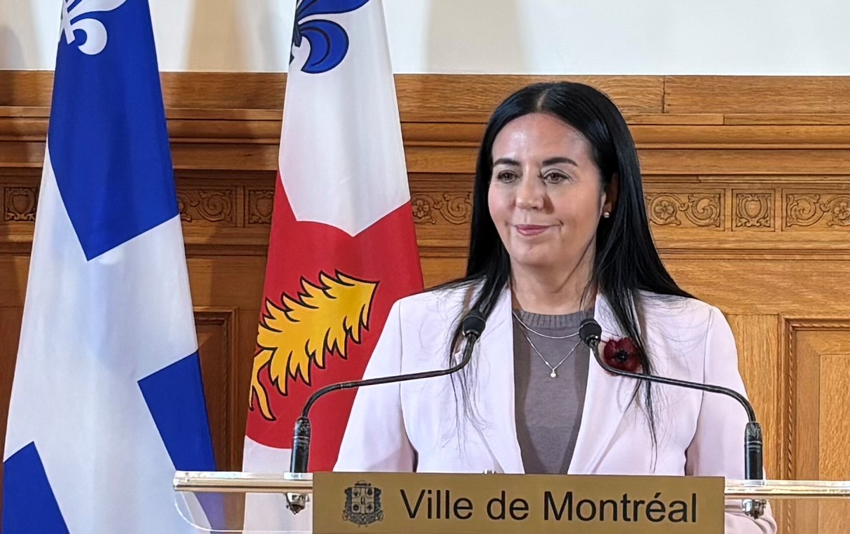 Soraya Martinez Ferrada en point de presse à l'hôtel de ville de Montréal devant des drapeaux du Québec et de Montréal.