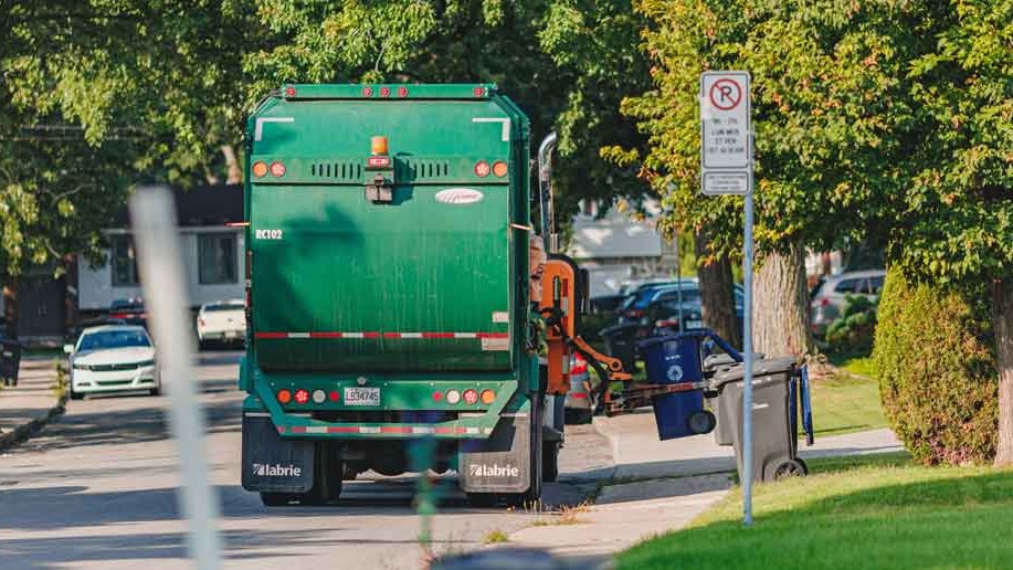 Un camion de recyclage ramasse un bac bleu dans un secteur résidentiel de Laval.