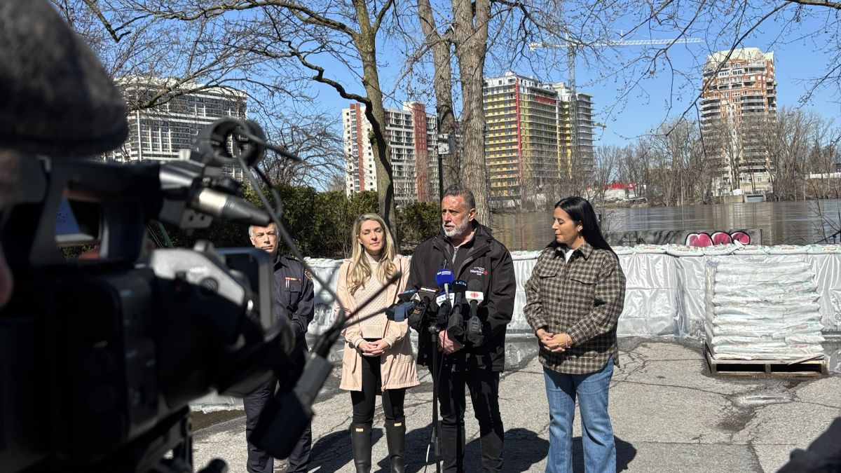 Effie Giannou, Jim Beis et Soraya Martinez Ferrada devant une digue empêchant une inondation de la rivière des Prairies.