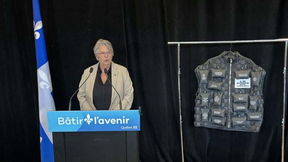 La ministre Chantal Rouleau avec une veste pesée pour illustrer le "pois des préjugés" liés à l'itinérance.